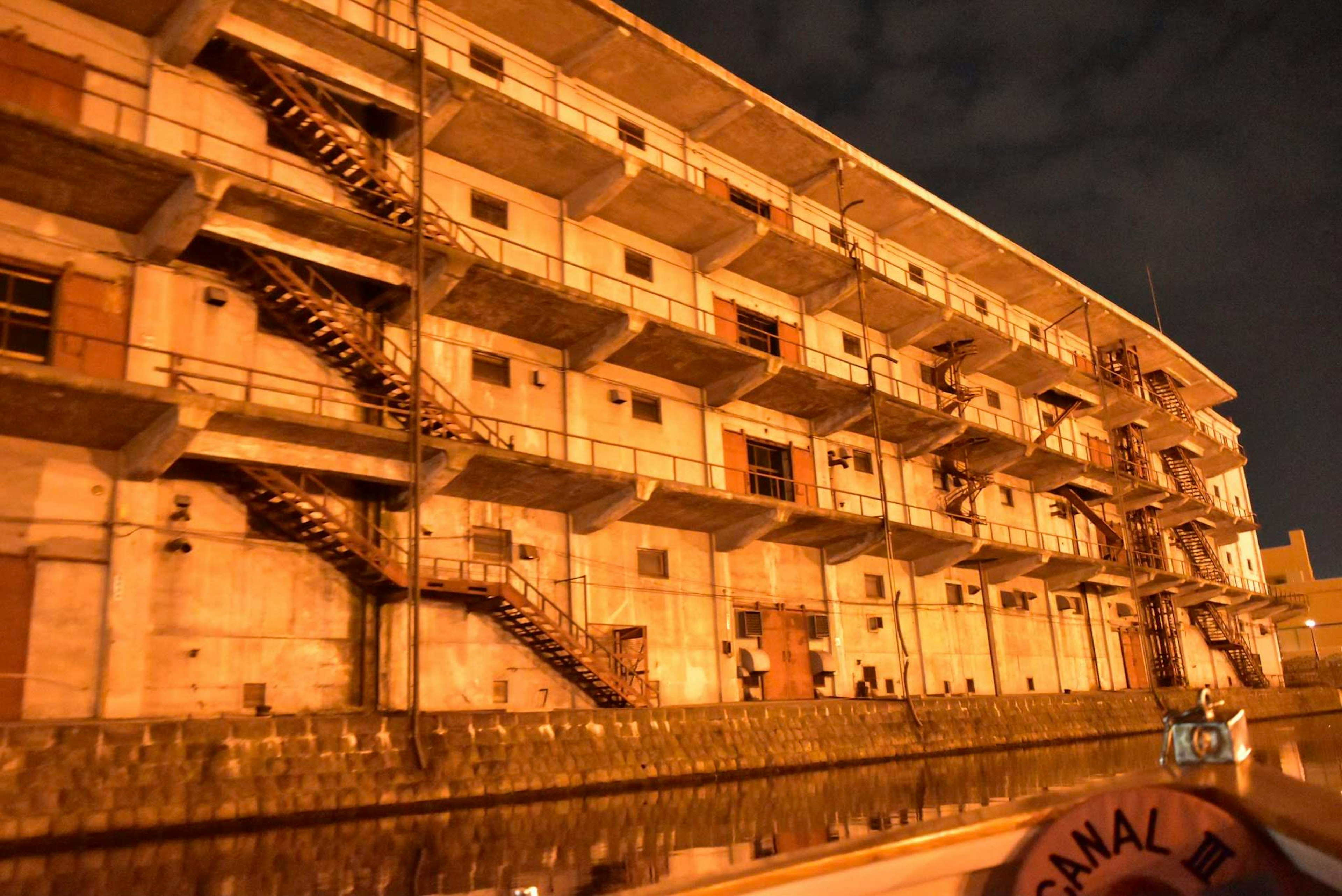 Exterior view of an old apartment building at night featuring metal staircases and windows