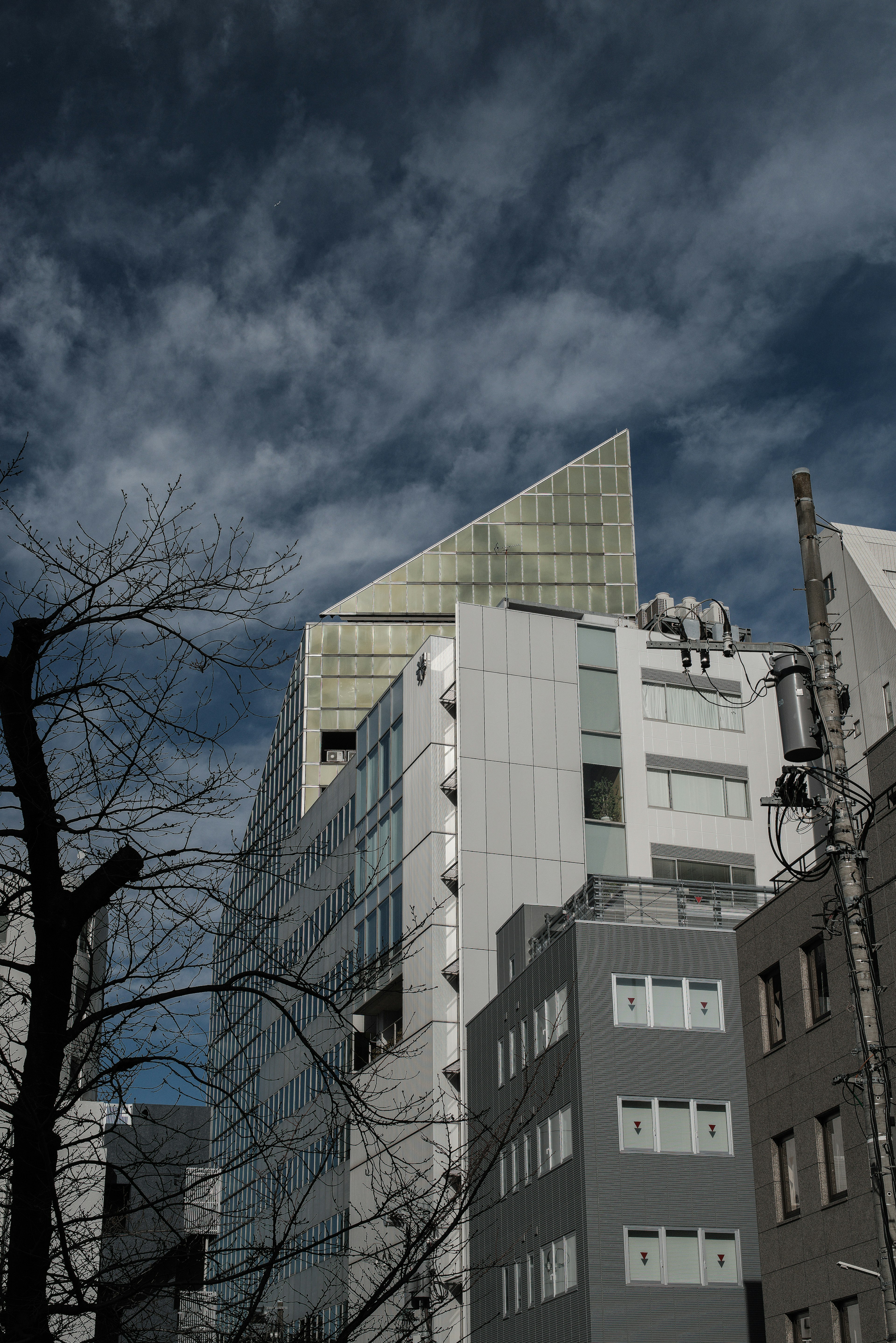 現代的なビルの上部に鋭い三角形の屋根が特徴的な風景