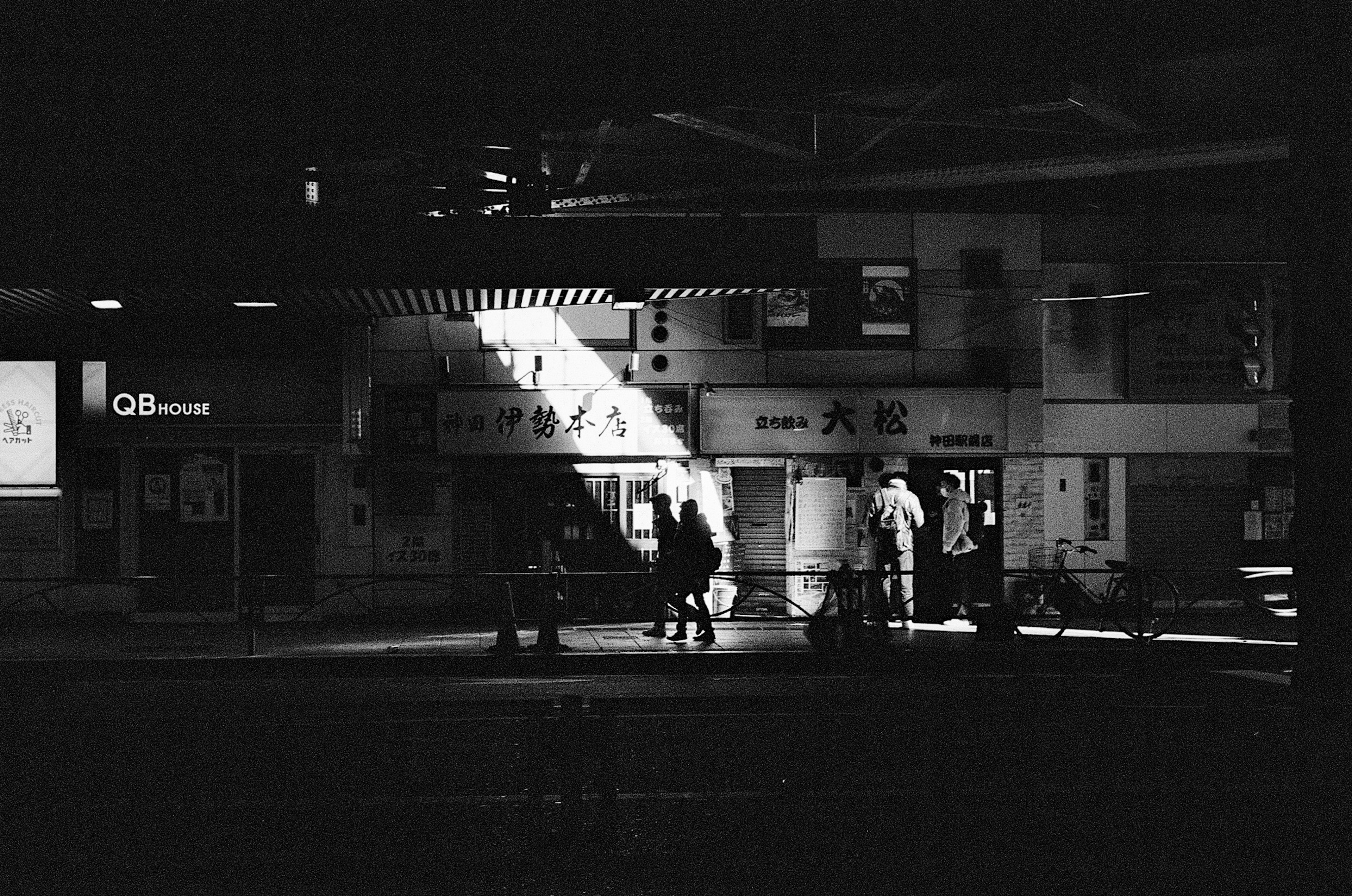 Silhouette of people in a dimly lit train station with light streaming in