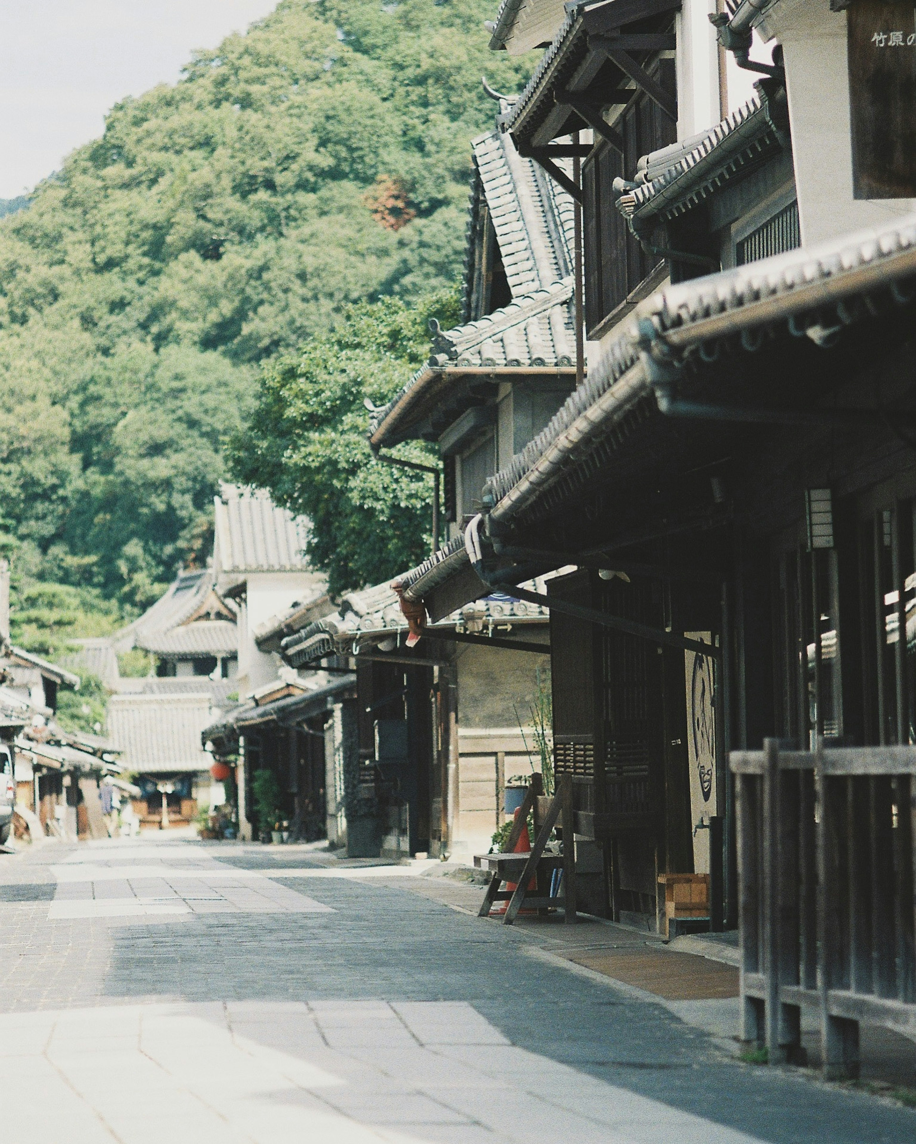 Ruhige japanische Straße mit traditionellen Gebäuden und grünen Hügeln