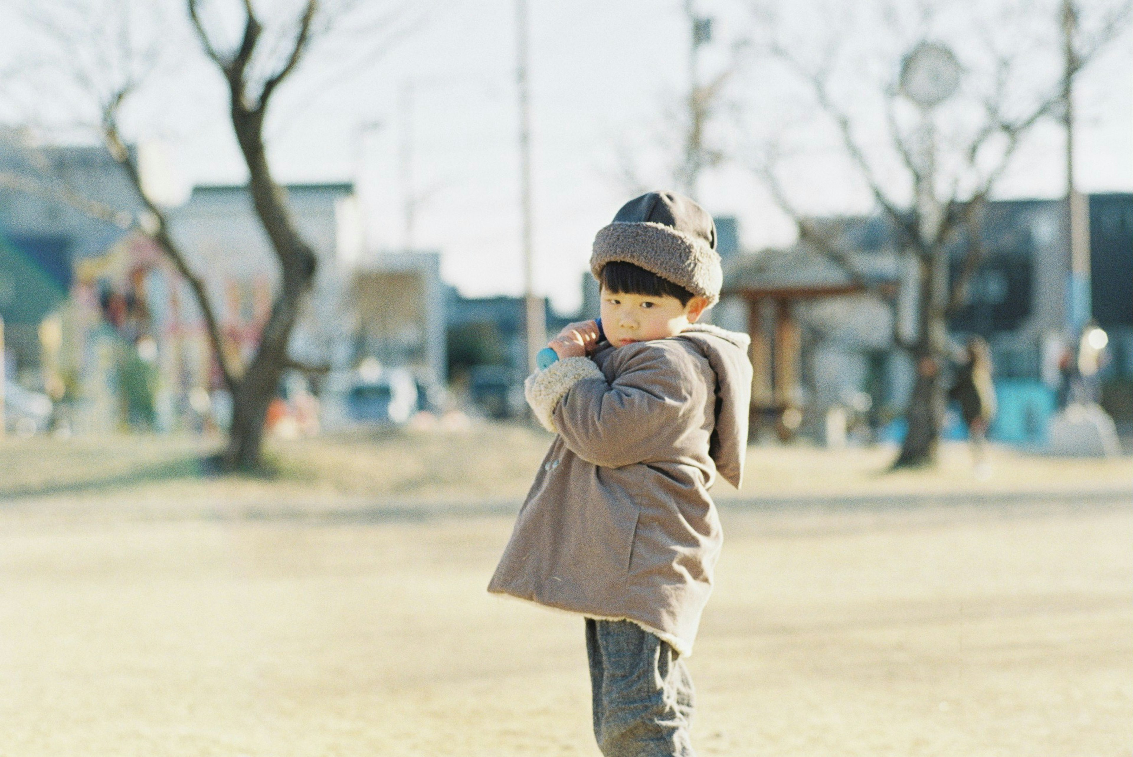 Bambino in un parco che indossa abiti caldi in una giornata fresca