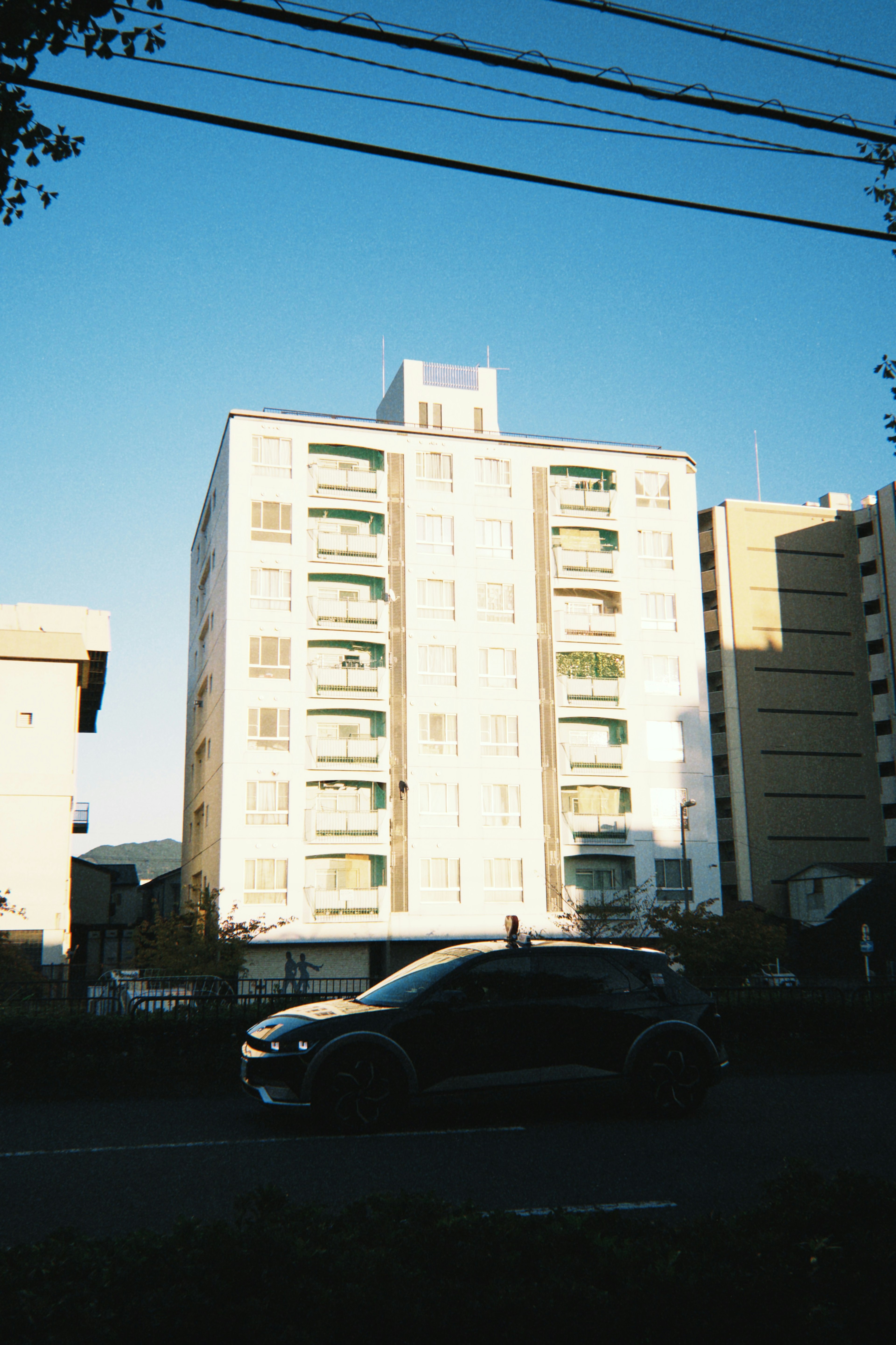 Edificio bianco sotto un cielo blu con un'auto nera