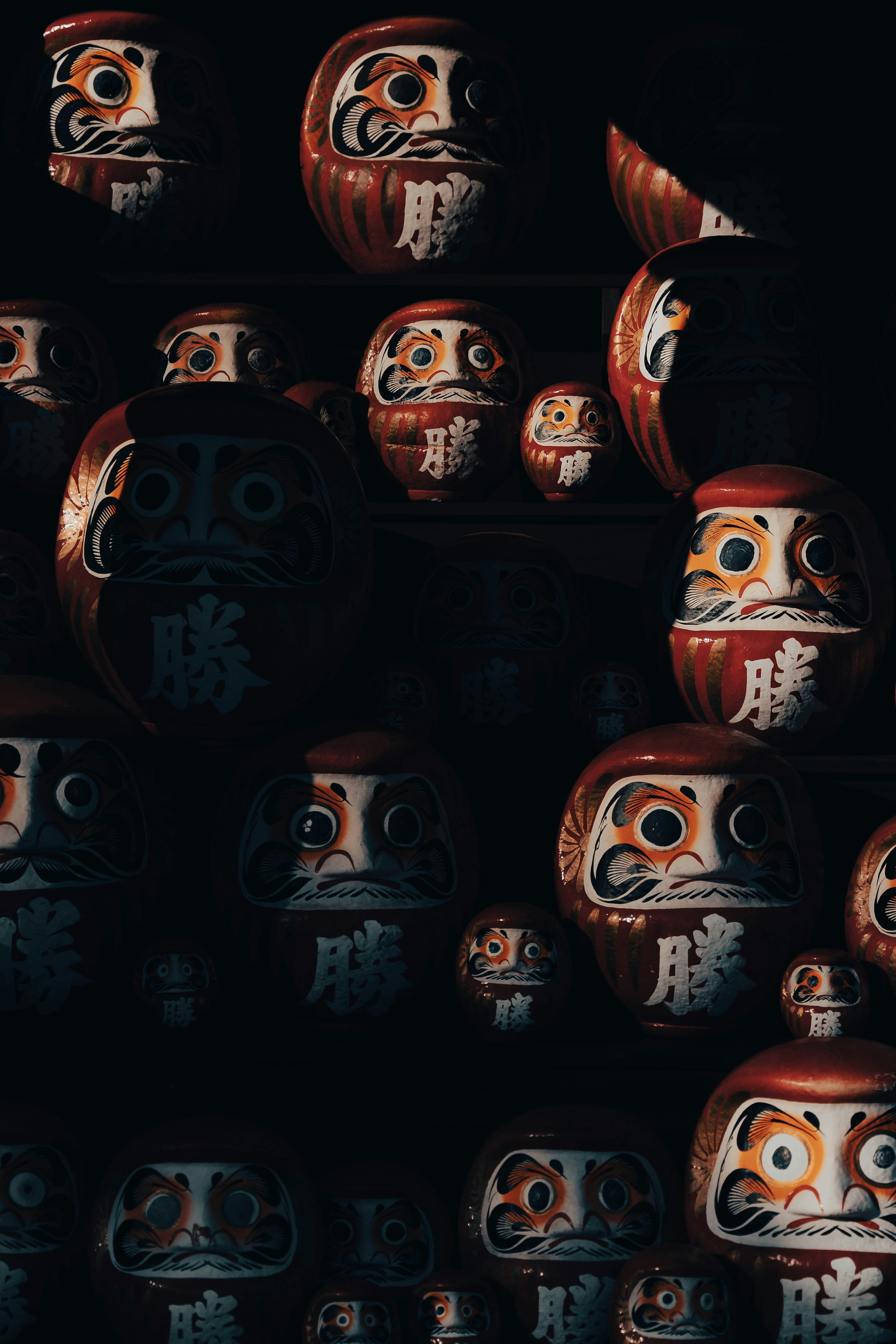 Varias muñecas Daruma coloridas dispuestas sobre un fondo negro