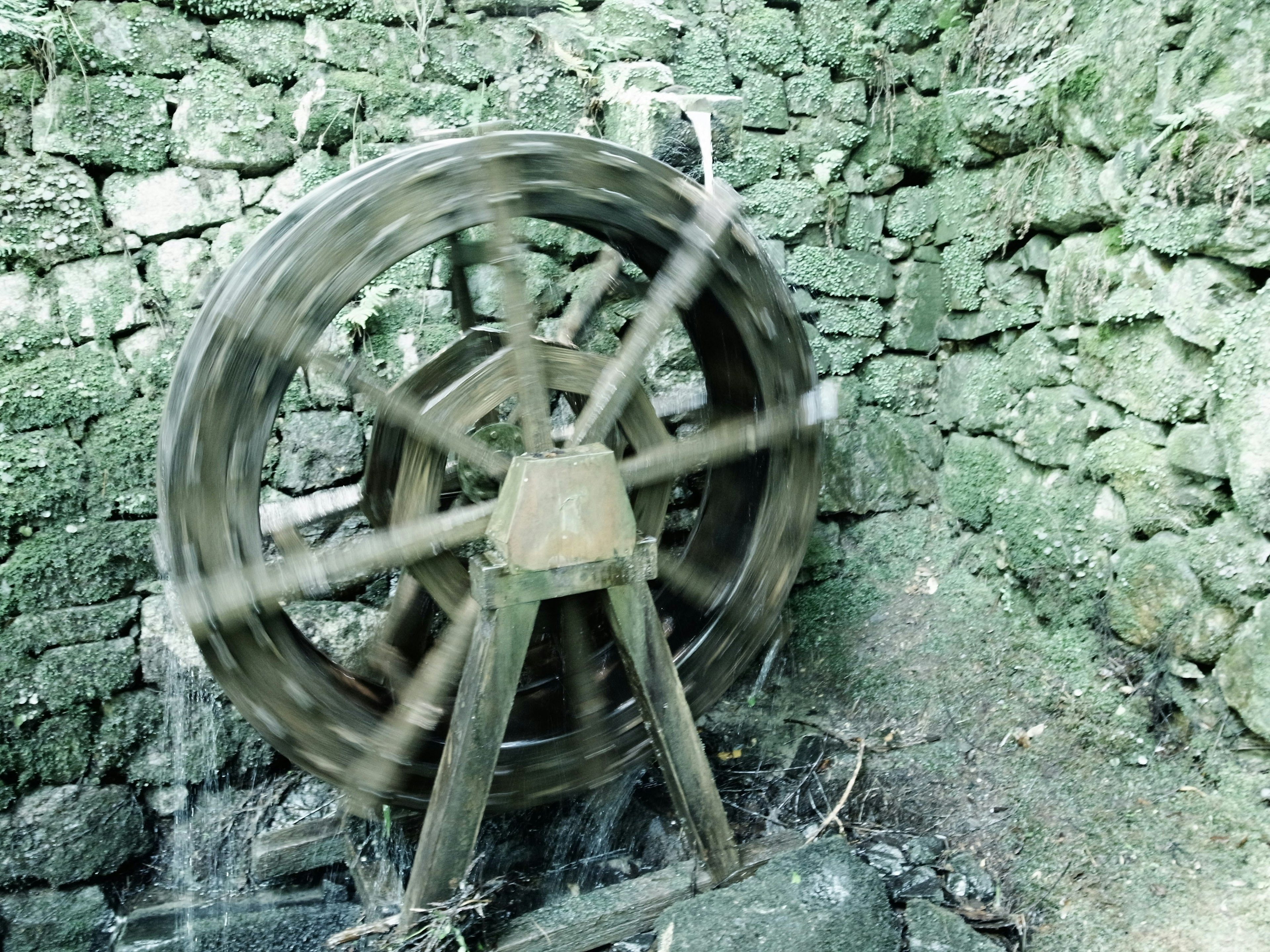 Roue à eau en mouvement contre un vieux mur en pierre