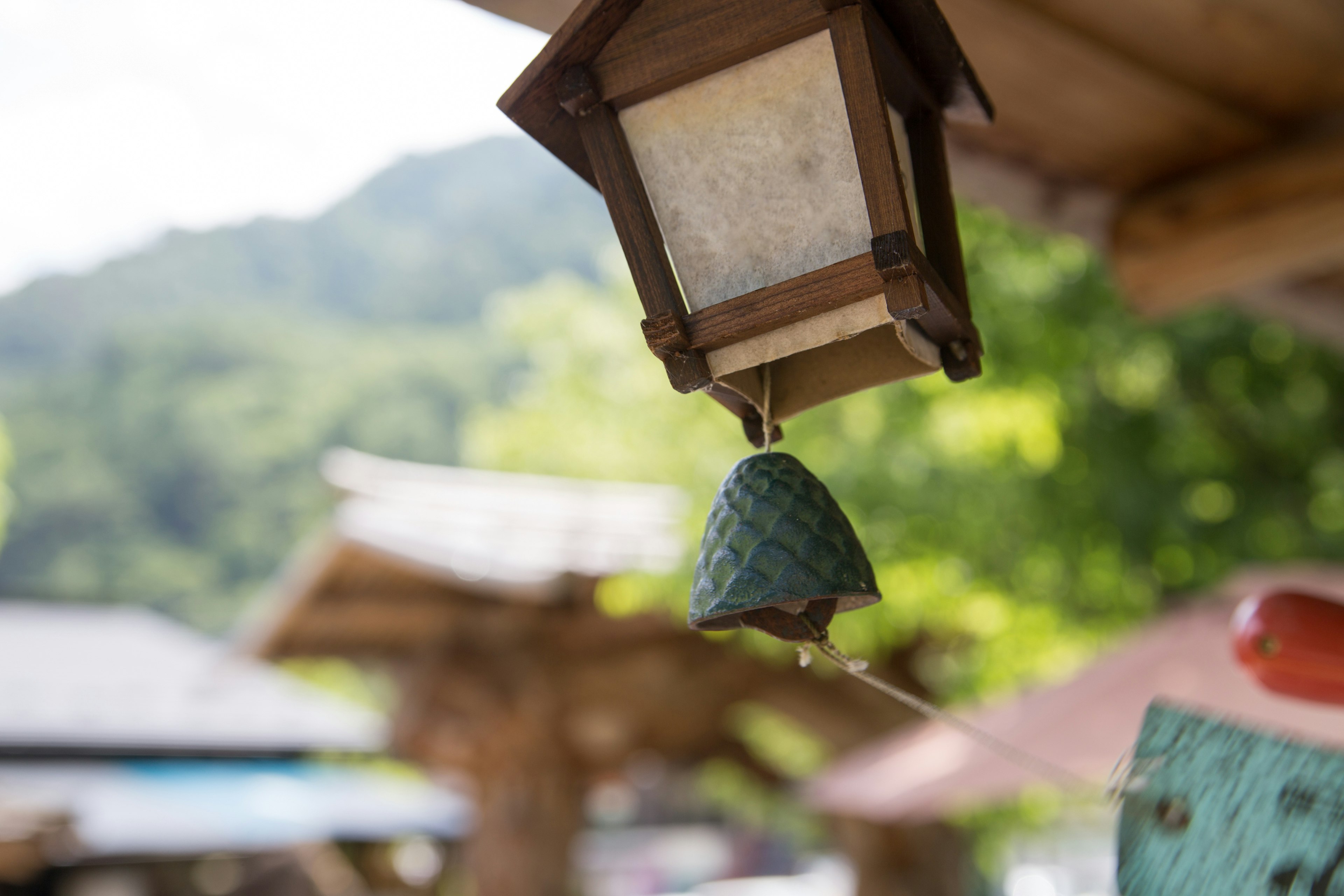 Lanterne en bois avec une cloche verte suspendue dans un cadre naturel