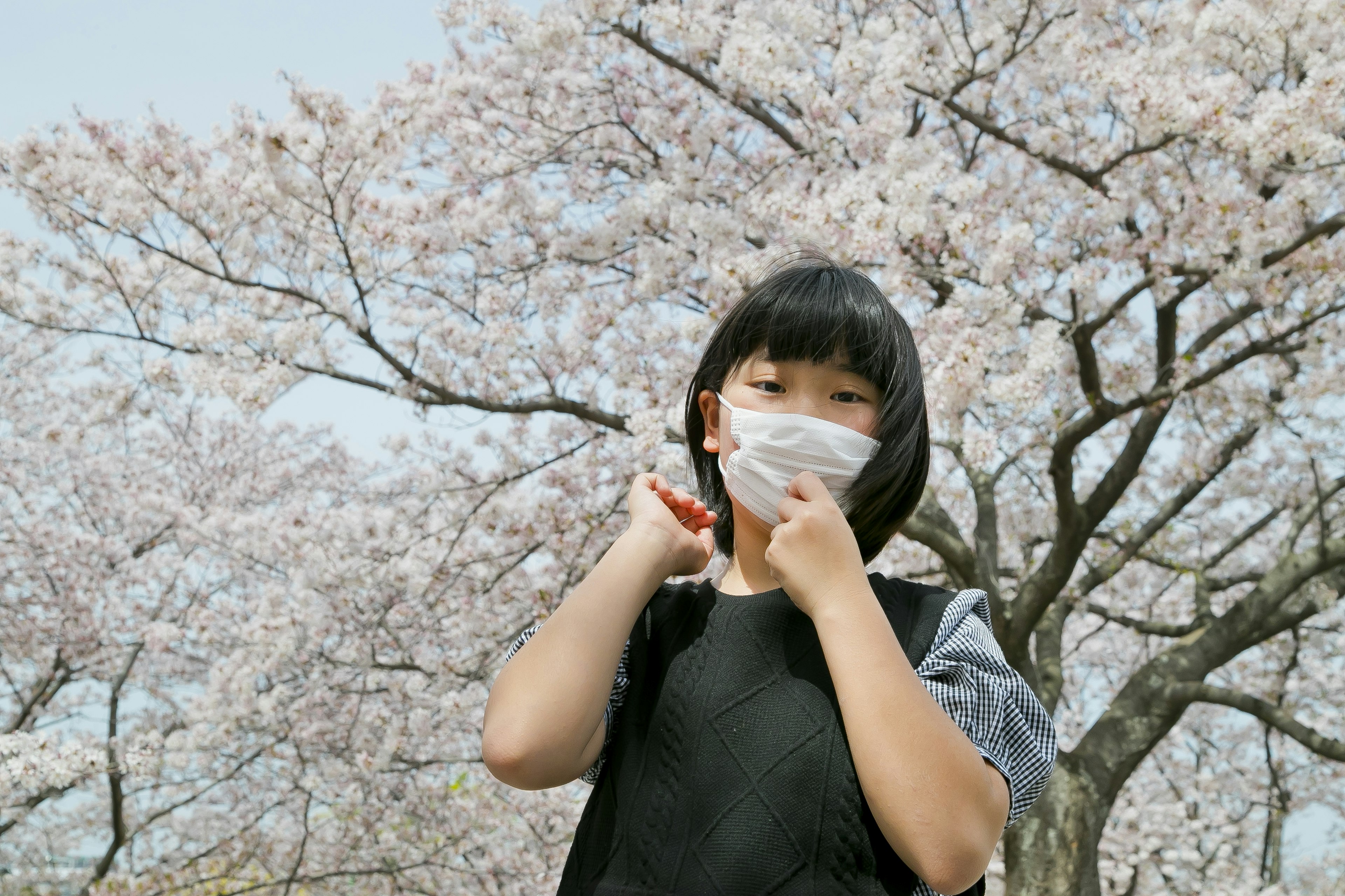 Mädchen mit Maske unter einem Kirschbaum