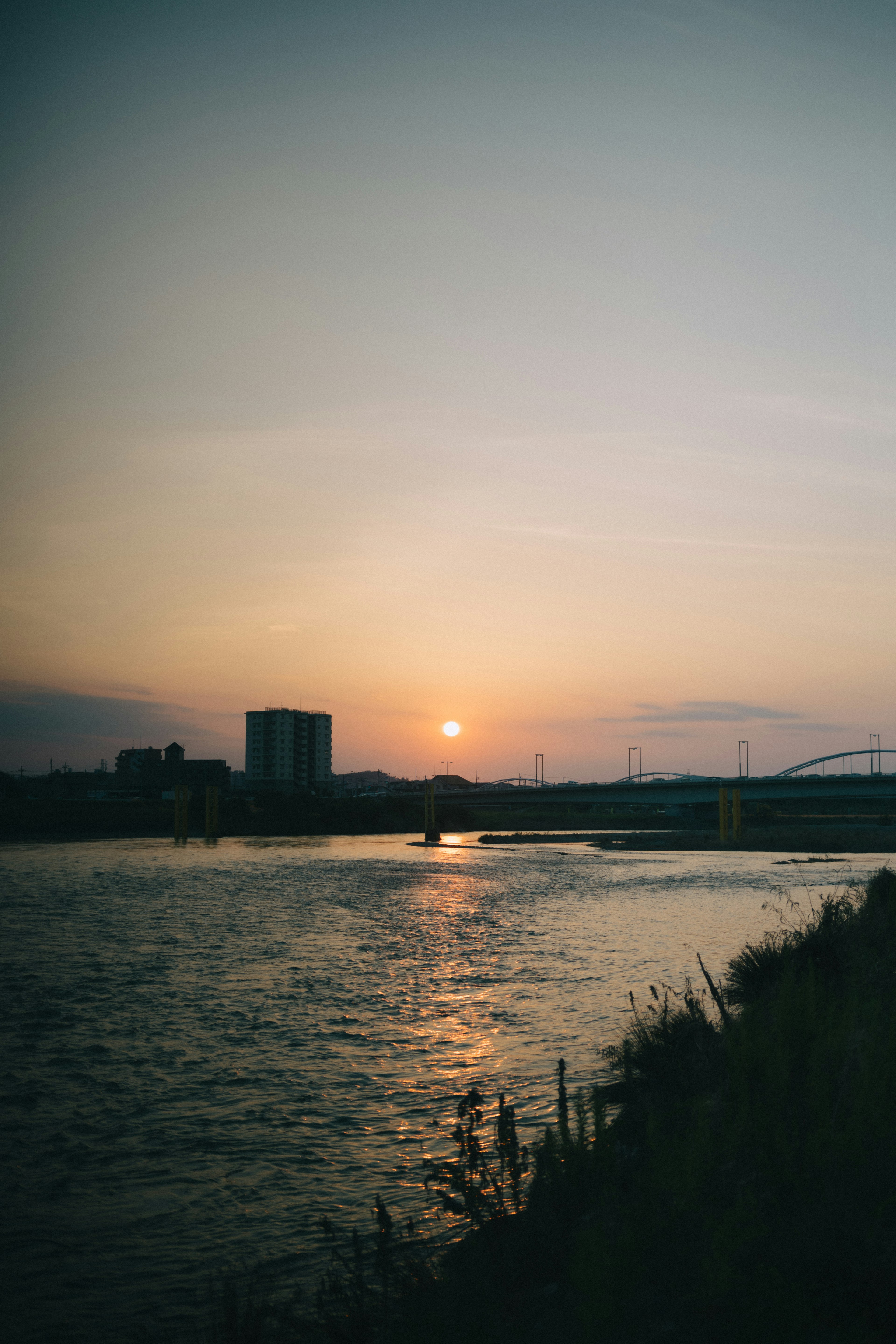 Flusslandschaft mit Sonnenuntergang und Gebäuden