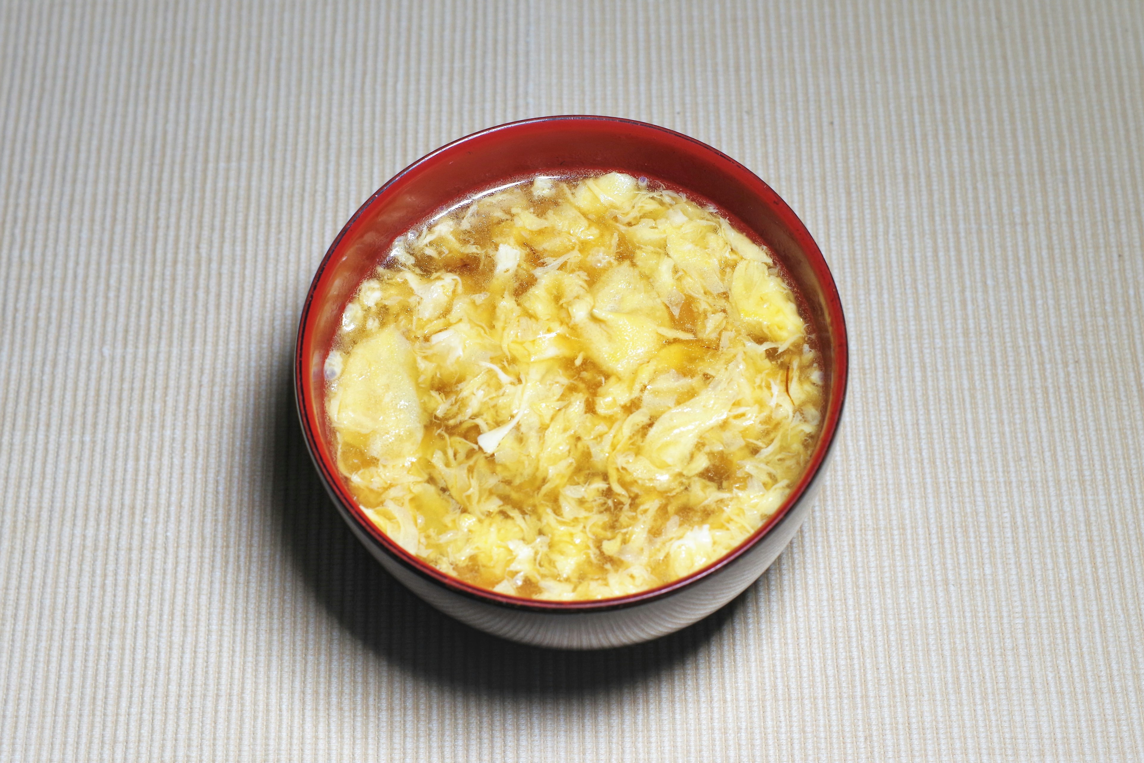 Un tazón de sopa de huevo servido en un plato rojo