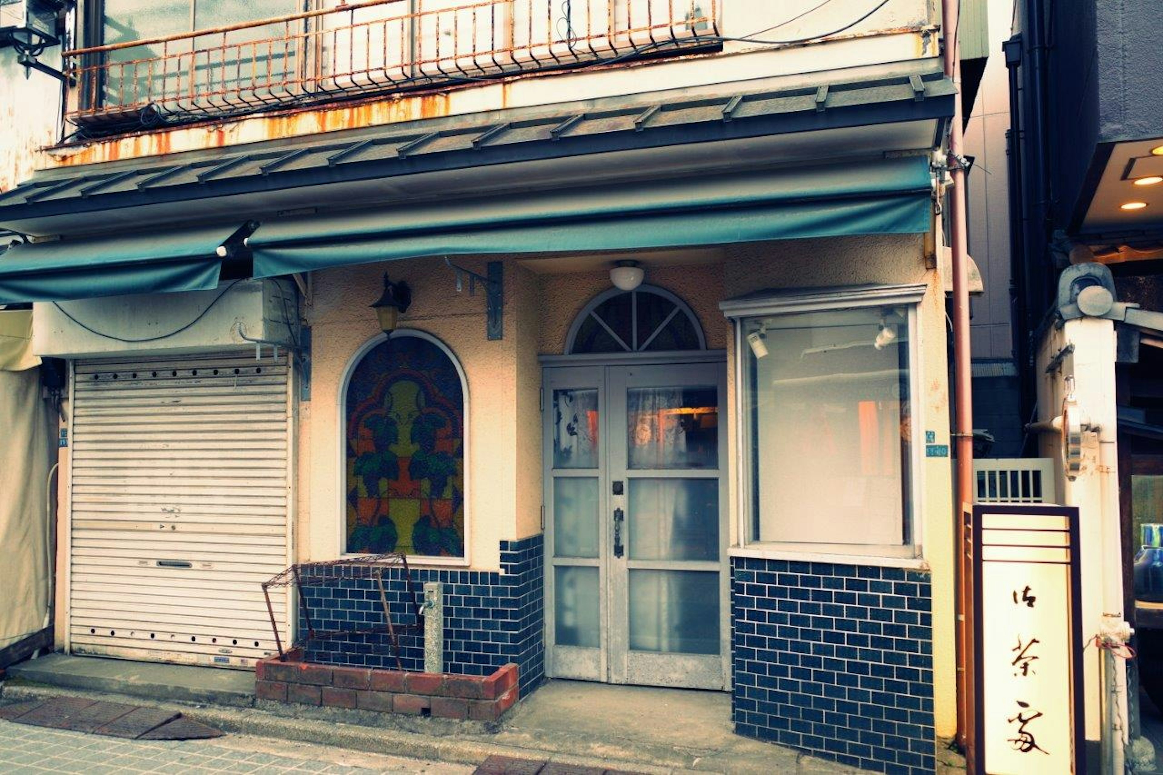 Fachada de un edificio antiguo con toldo azul y ventanas decorativas