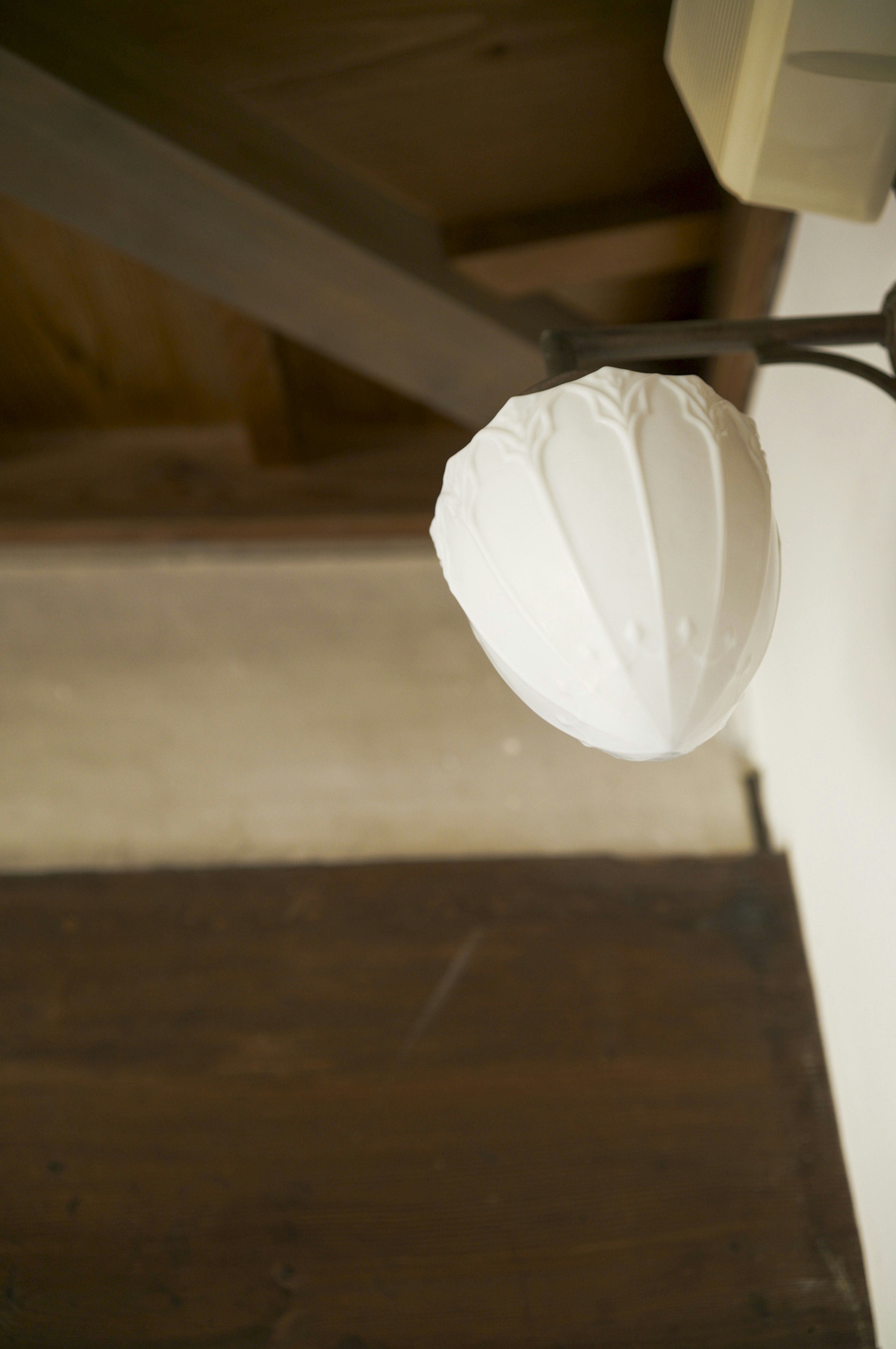 White lamp shade hanging from the ceiling in a wooden room