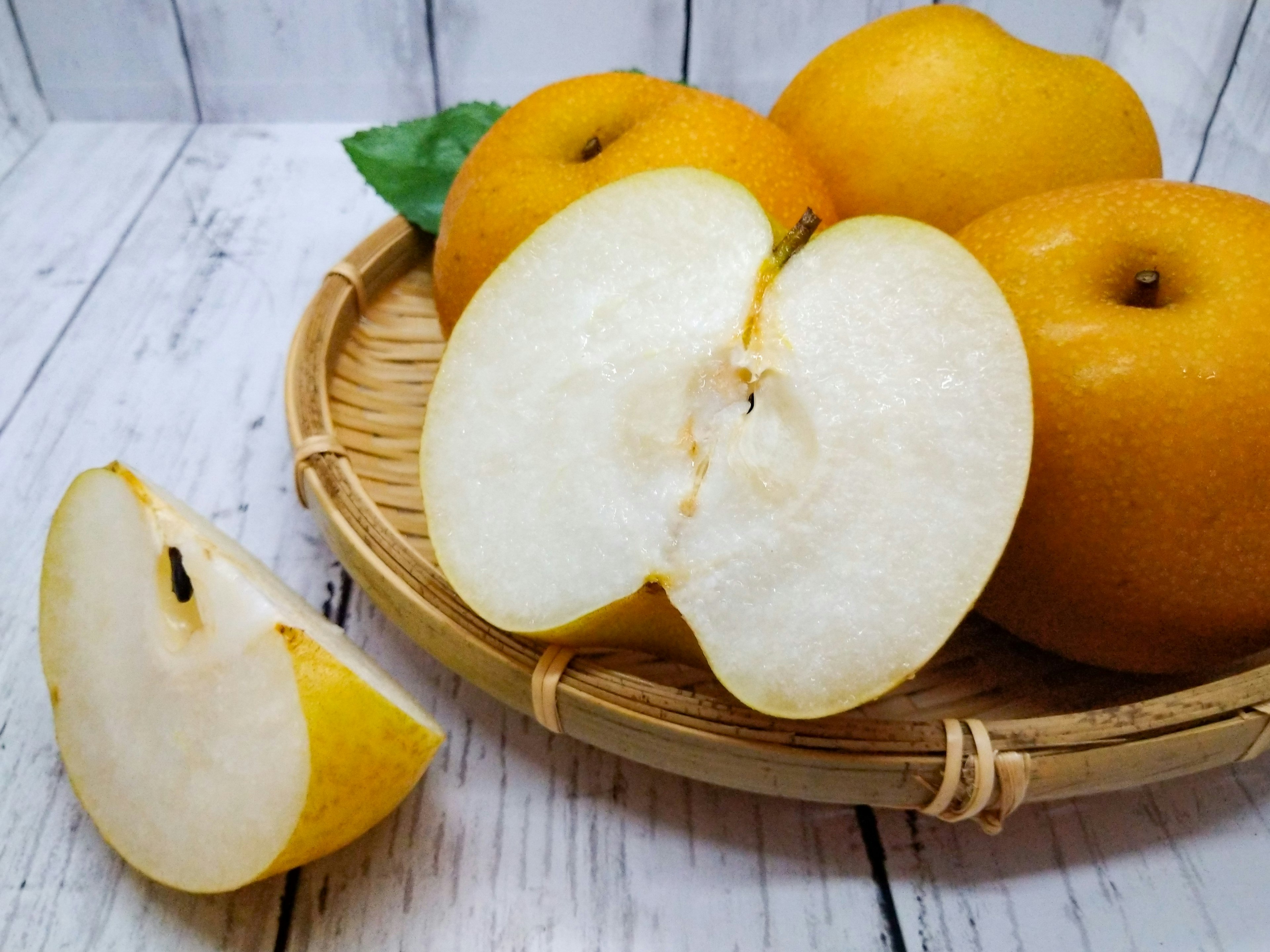 A wooden plate with yellow fruits including a halved pear