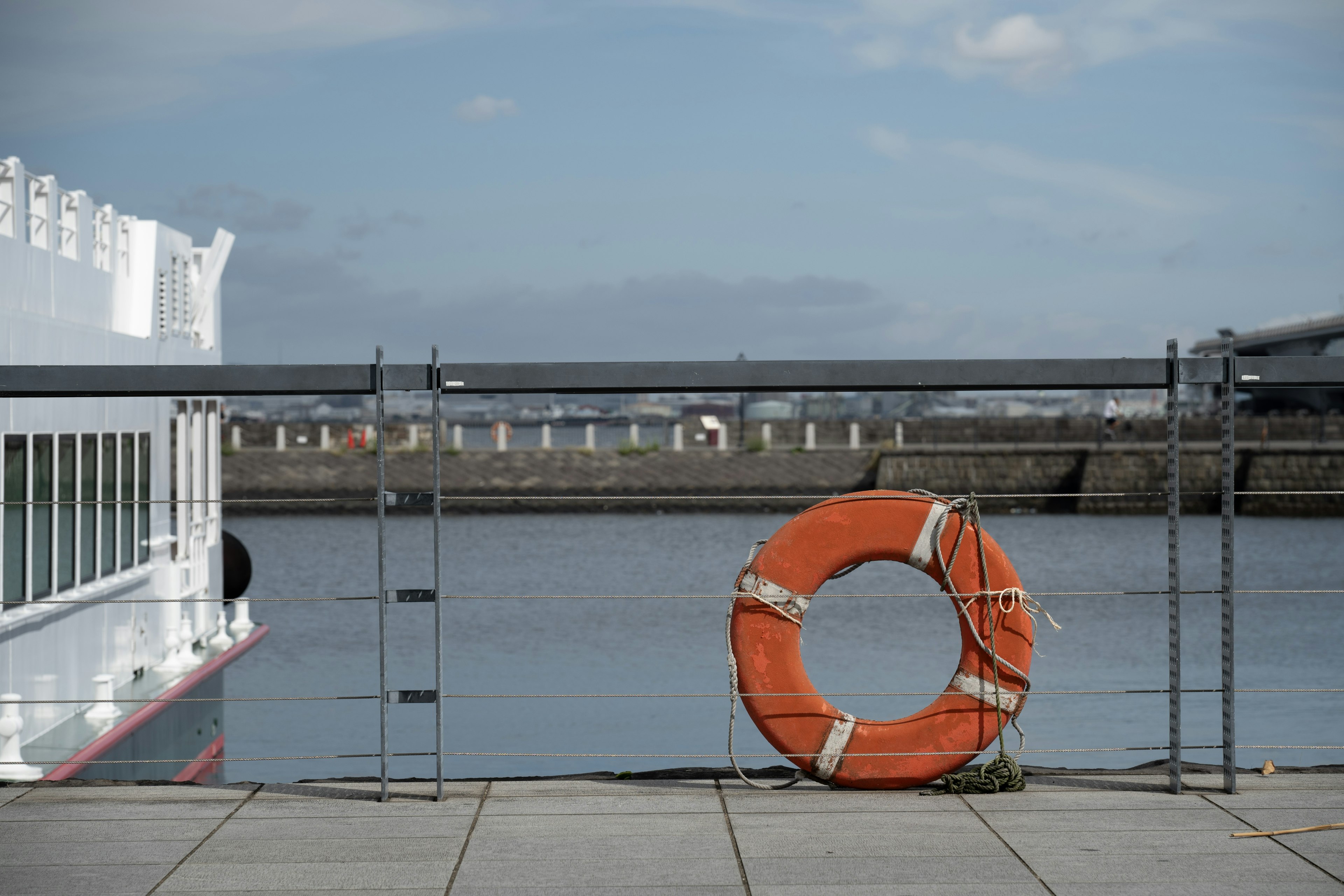 Une scène au bord de l'eau avec une bouée de sauvetage orange et un bateau