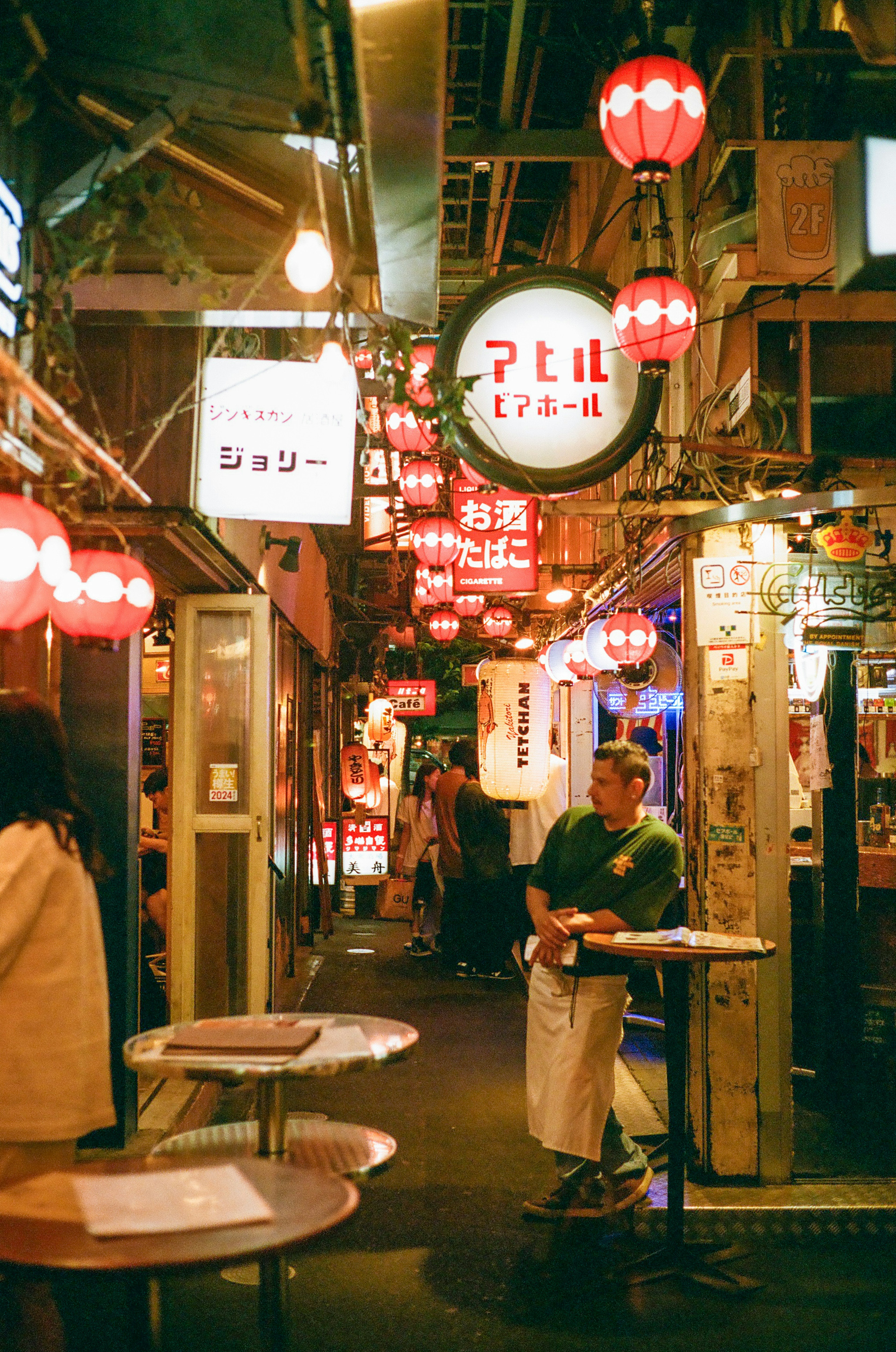 Un hombre sentado en un animado callejón japonés adornado con faroles rojos