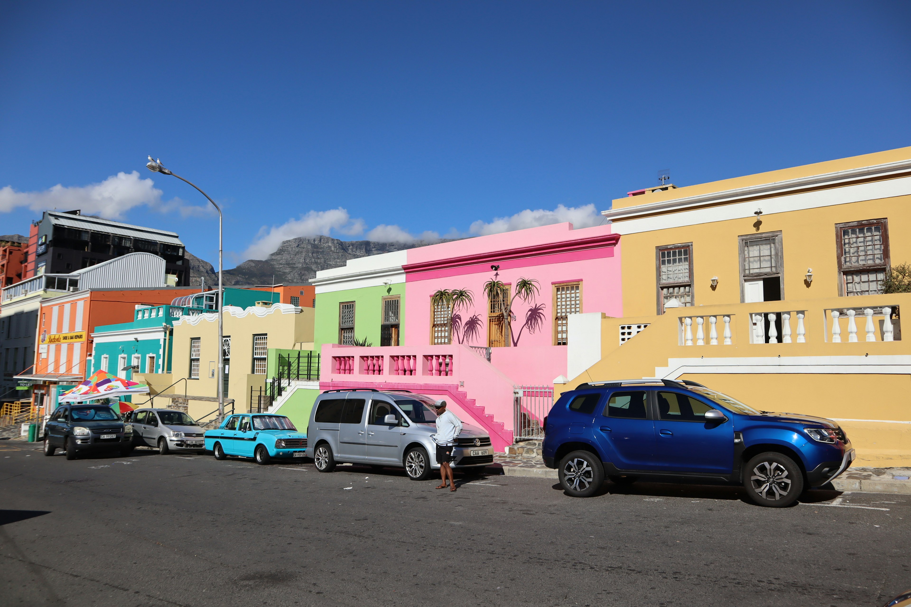 Case colorate allineate lungo la strada con veicoli parcheggiati