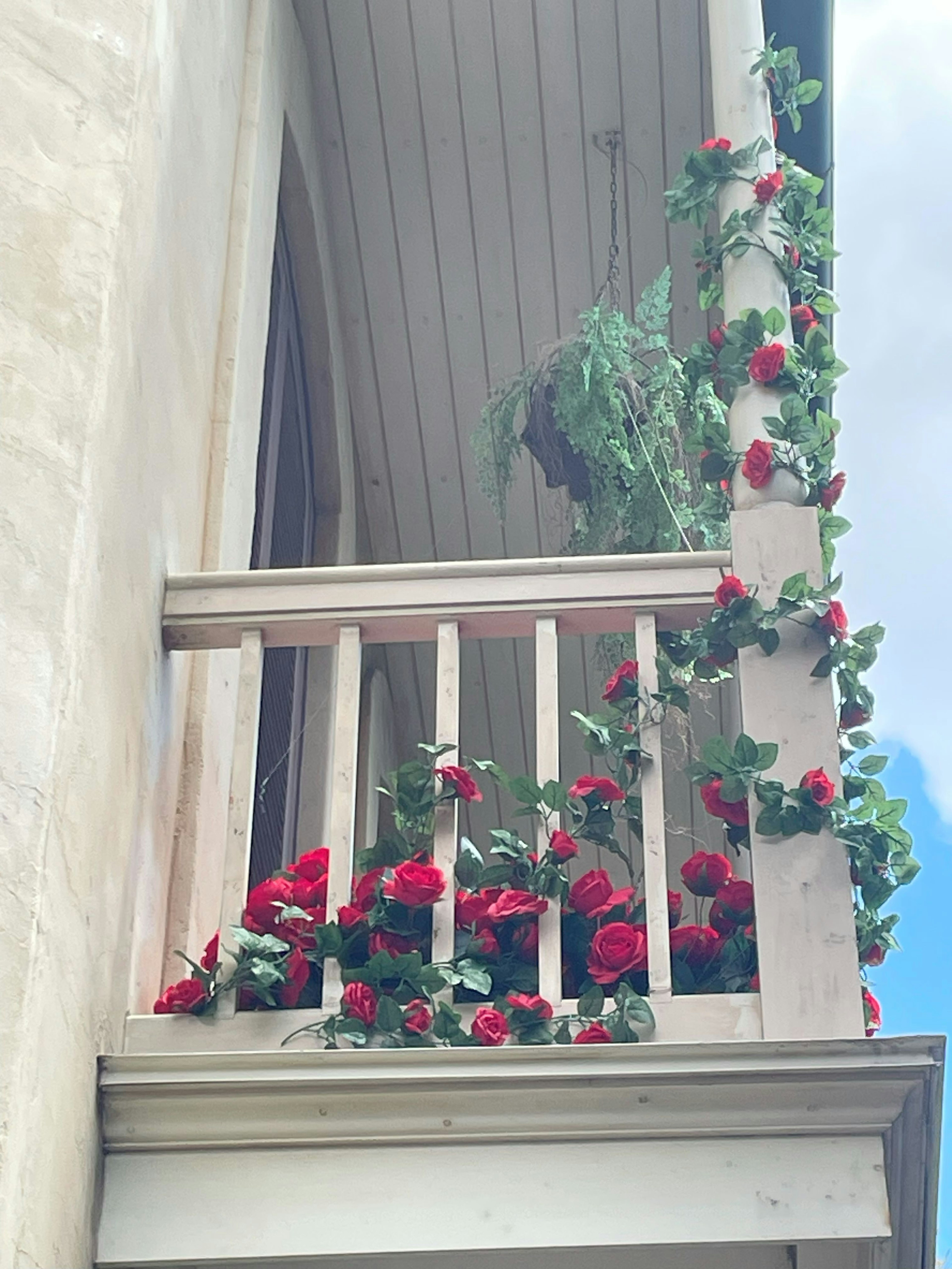 Balcón adornado con rosas rojas vibrantes y vegetación