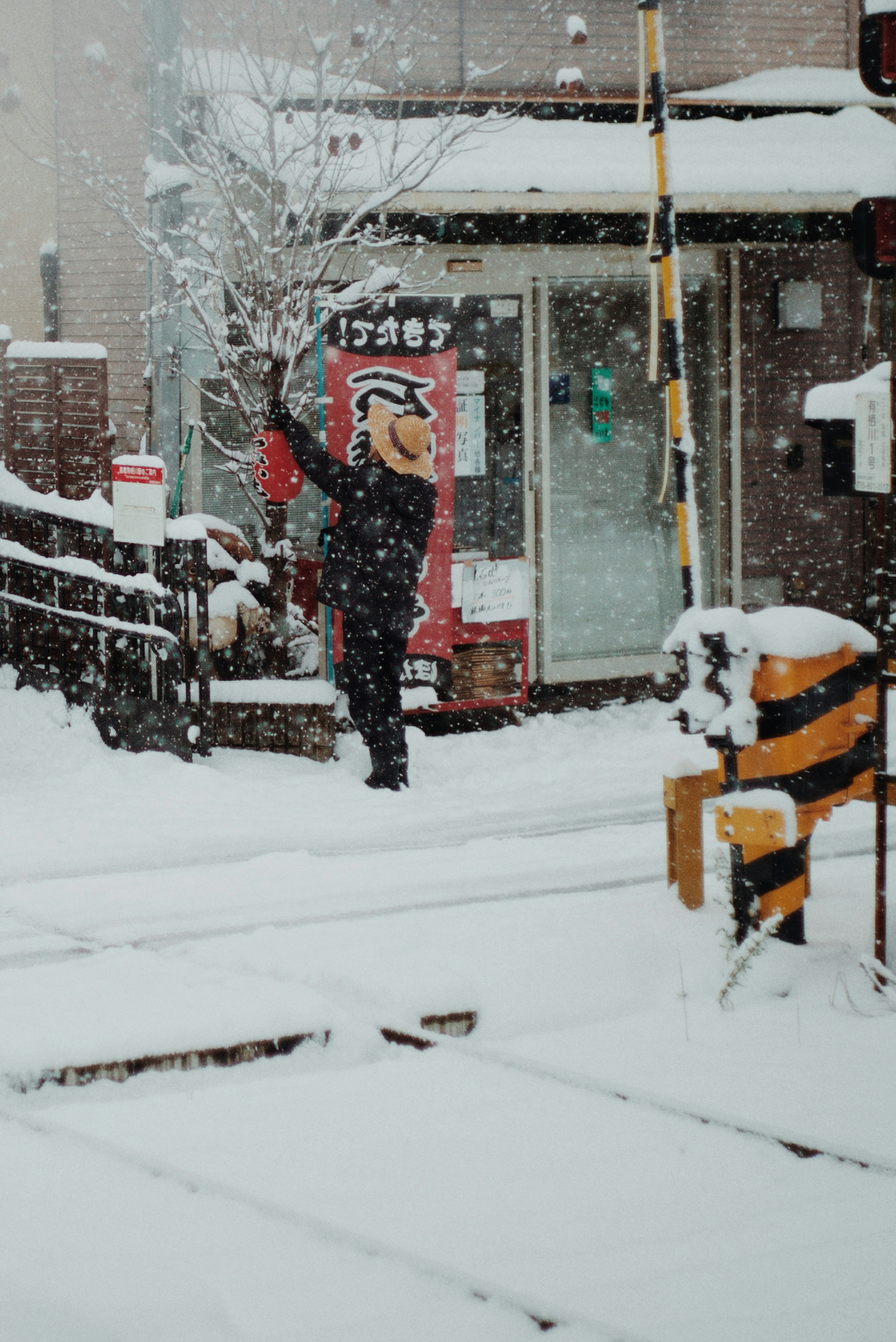 Person walking in snow with a train station sign in the background