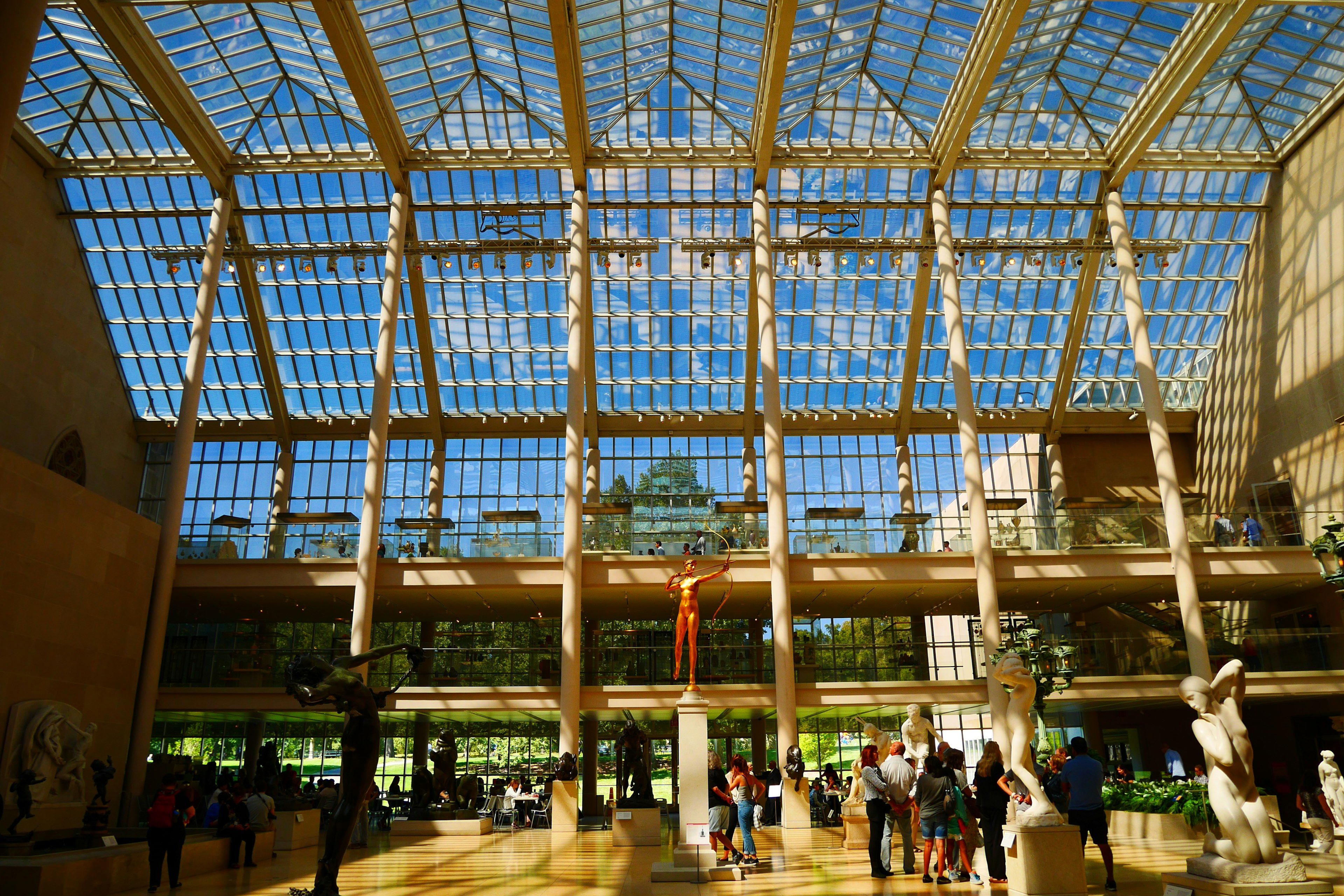 Spacious museum interior featuring a bright glass ceiling and sculptures