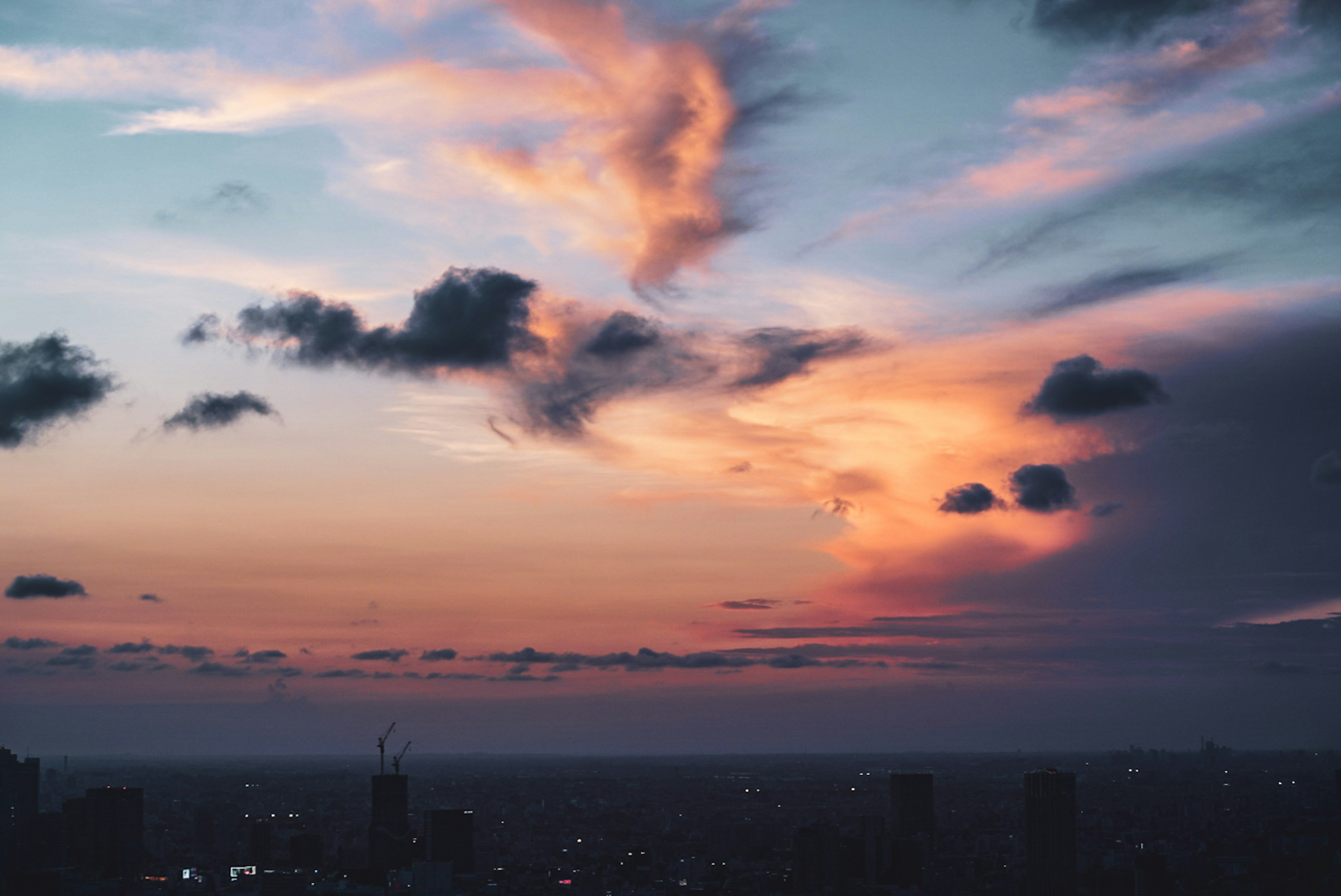 Beautiful sunset sky with colorful clouds and distant city lights