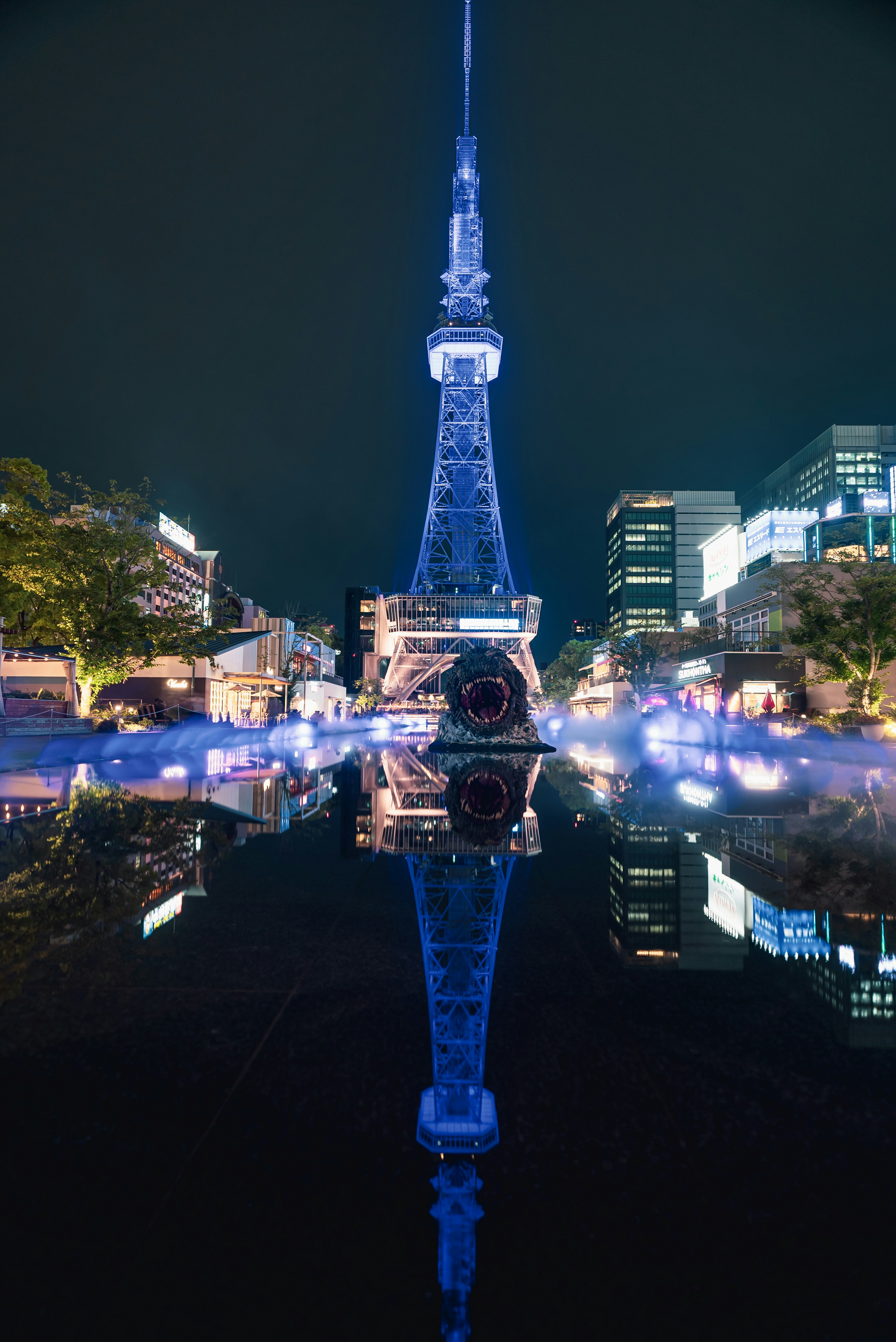 Menara TV Nagoya diterangi biru memantulkan di air saat malam