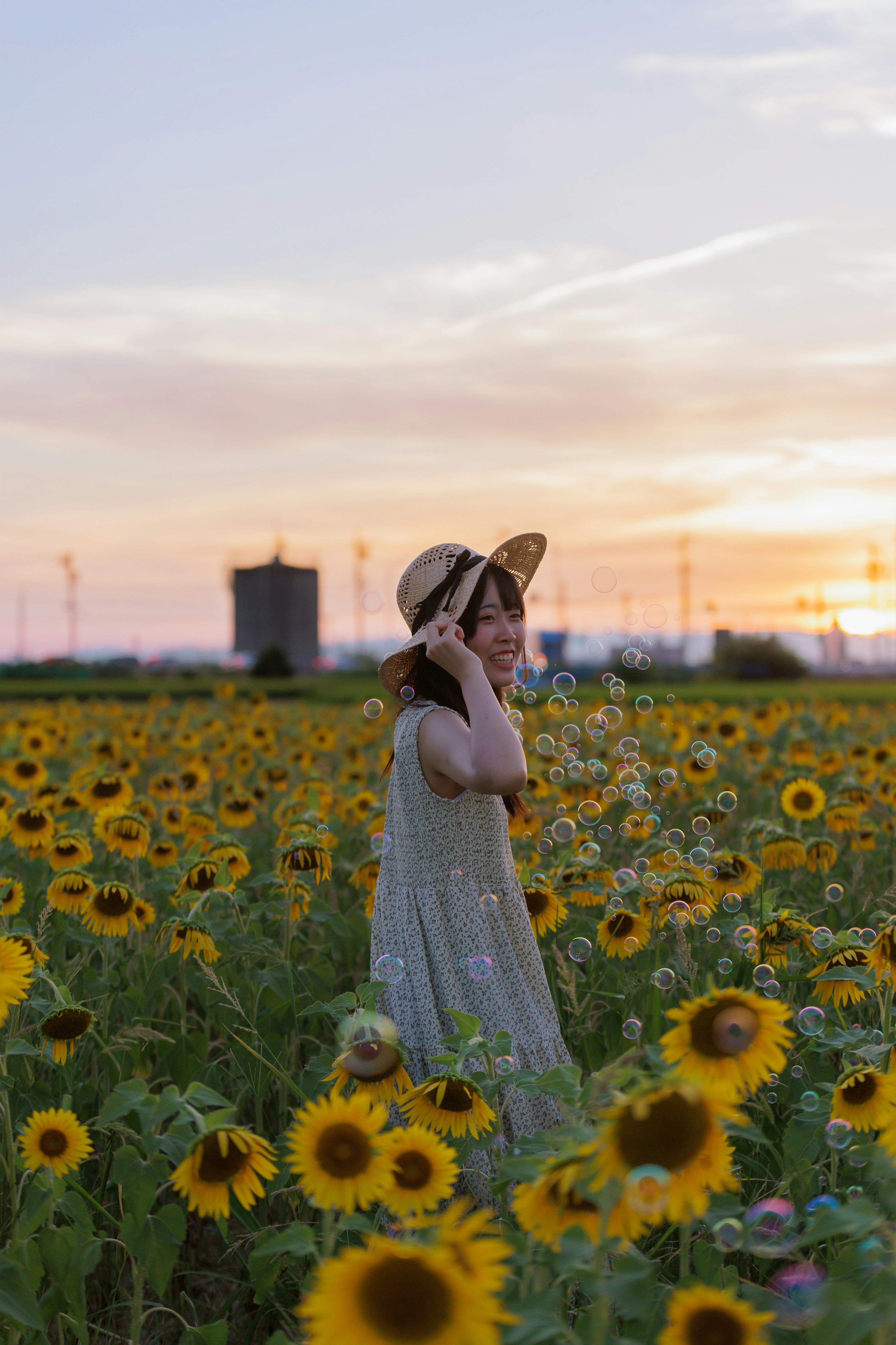 ひまわり畑で夕焼けの中に立つ女性の姿