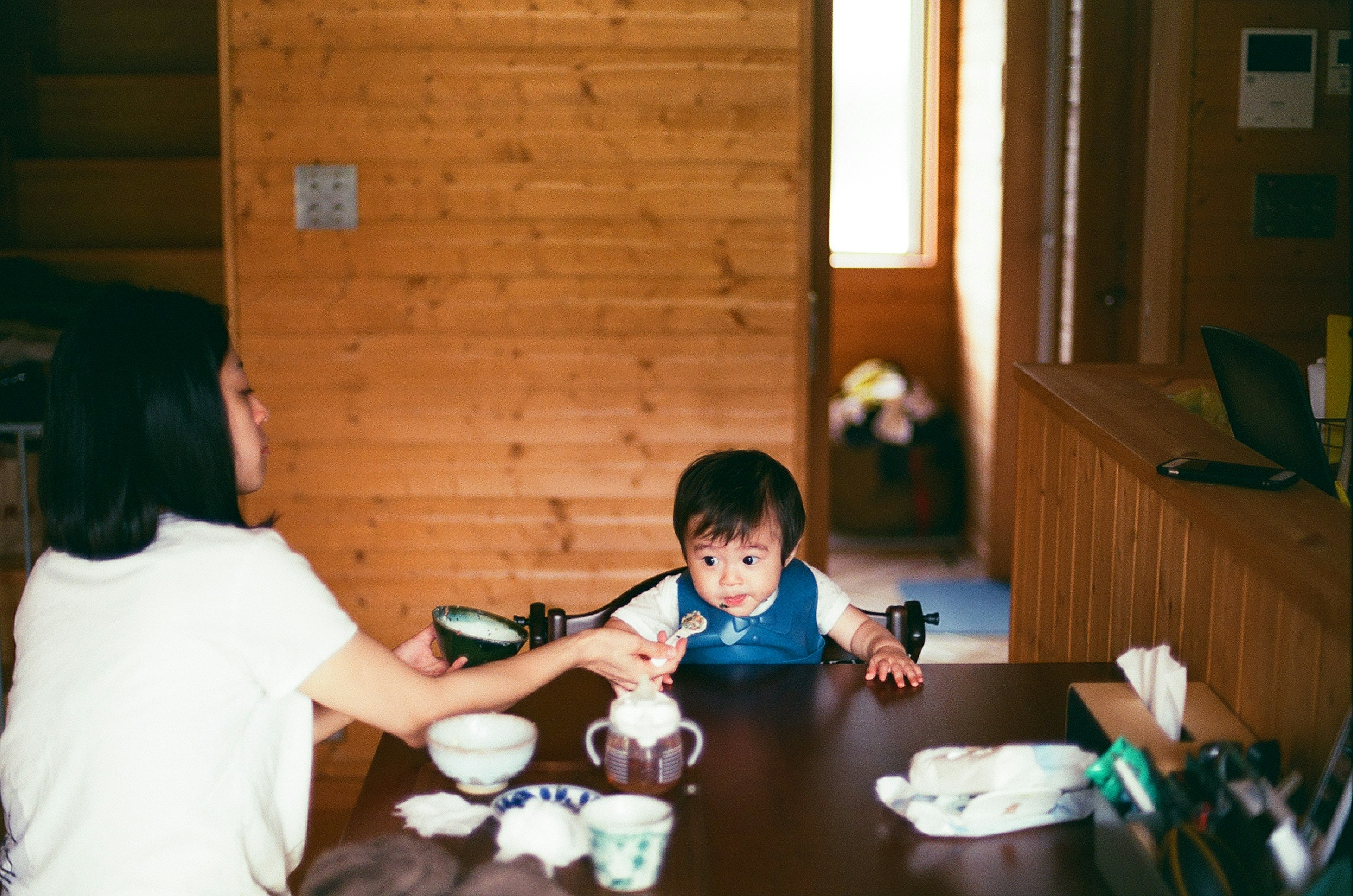 A mother feeding her child in a cozy wooden dining space