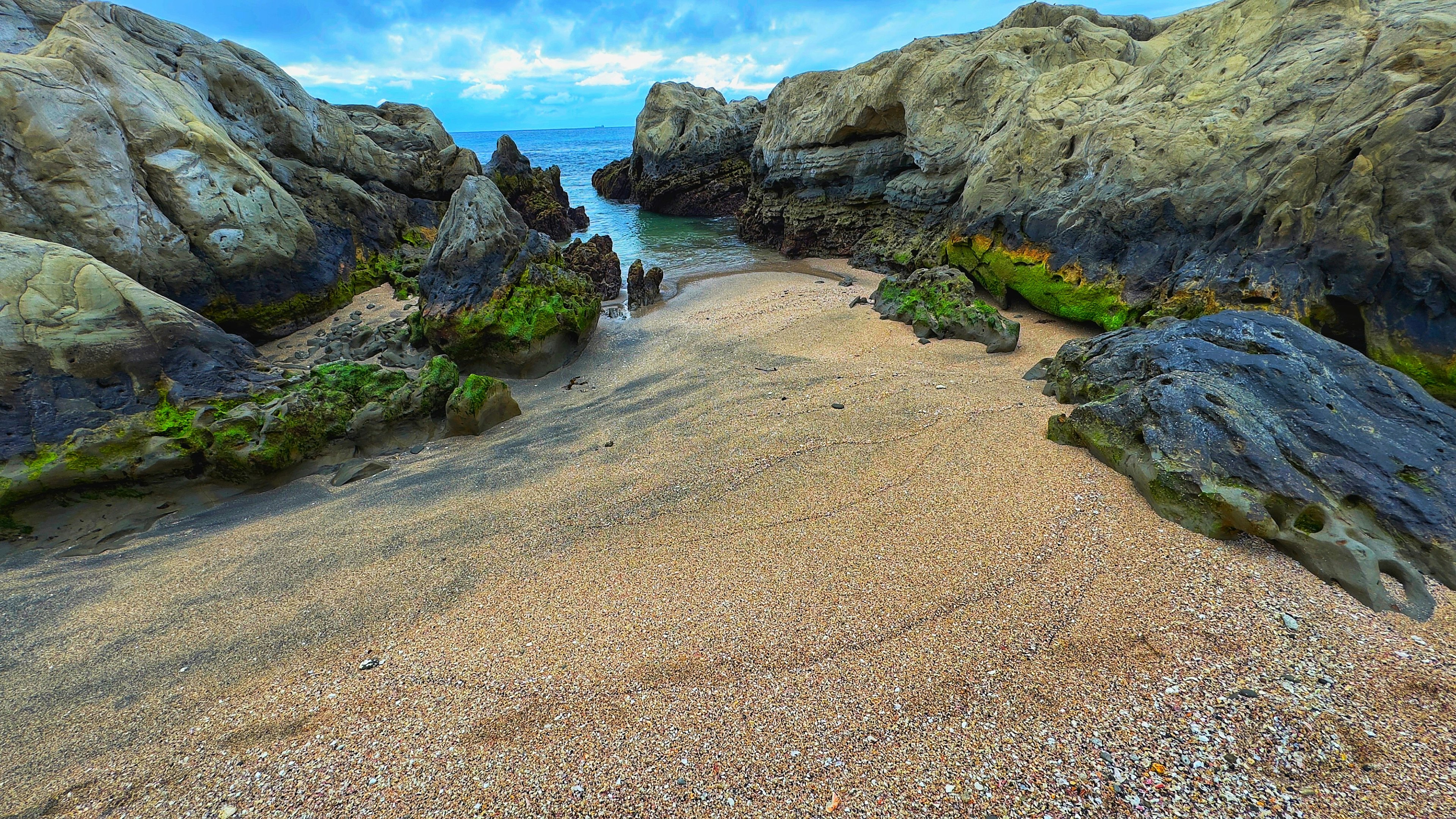 Scena di spiaggia circondata da rocce con sabbia e mare blu