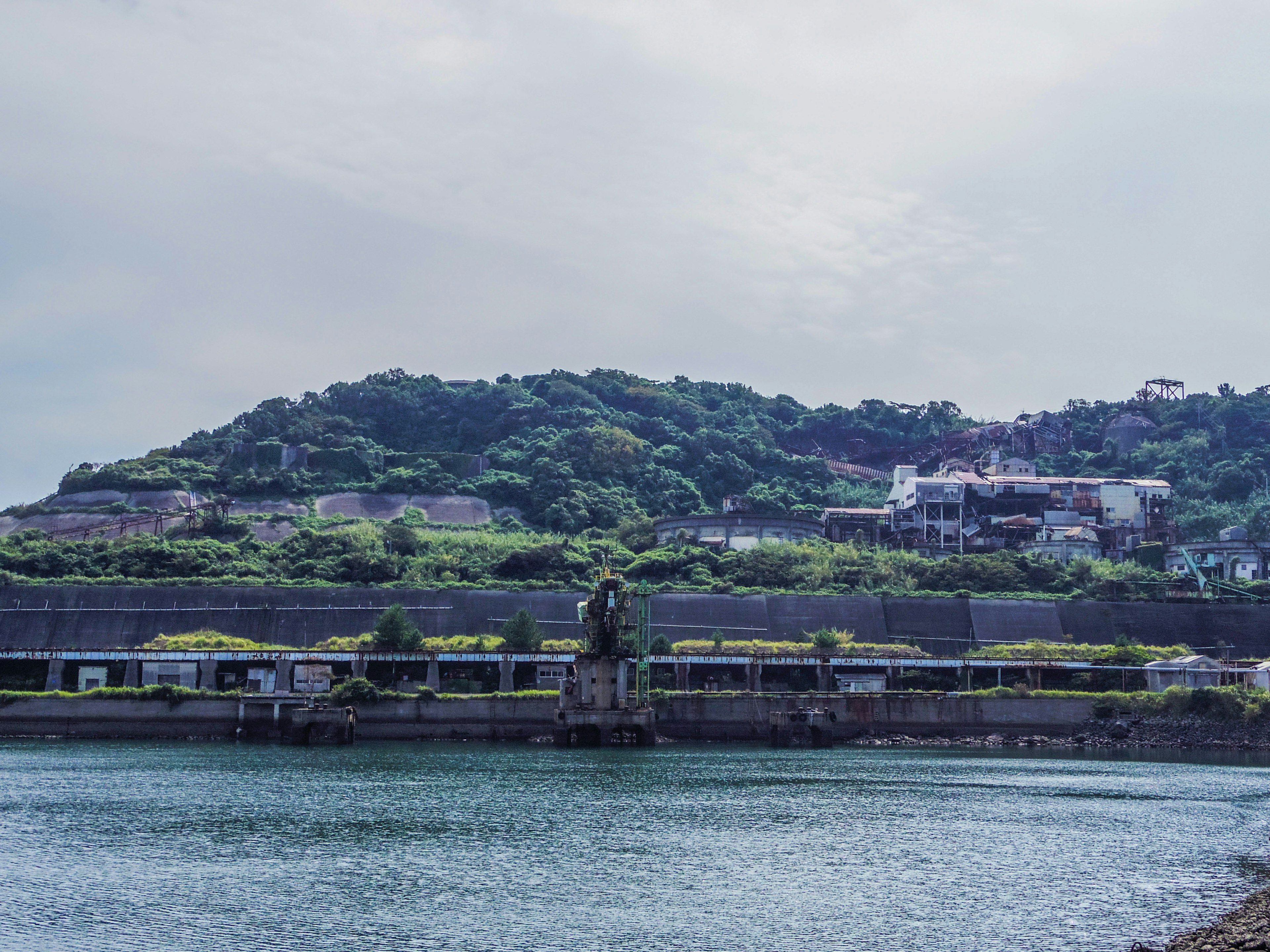 Vue panoramique d'un plan d'eau avec une ancienne structure et une colline verte en arrière-plan