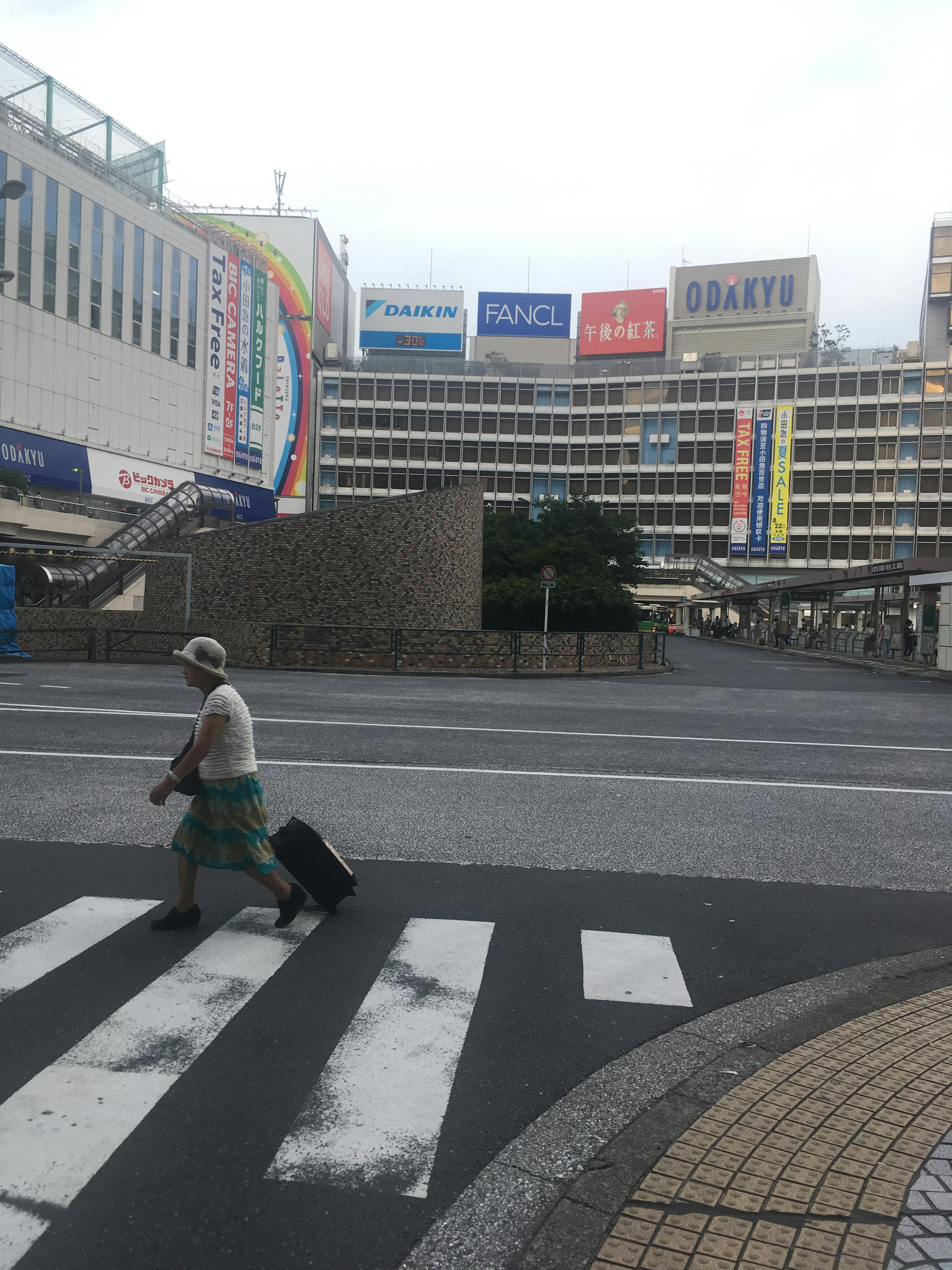 Reisender überquert die Straße mit Gepäck und Gebäudeschildern im Hintergrund