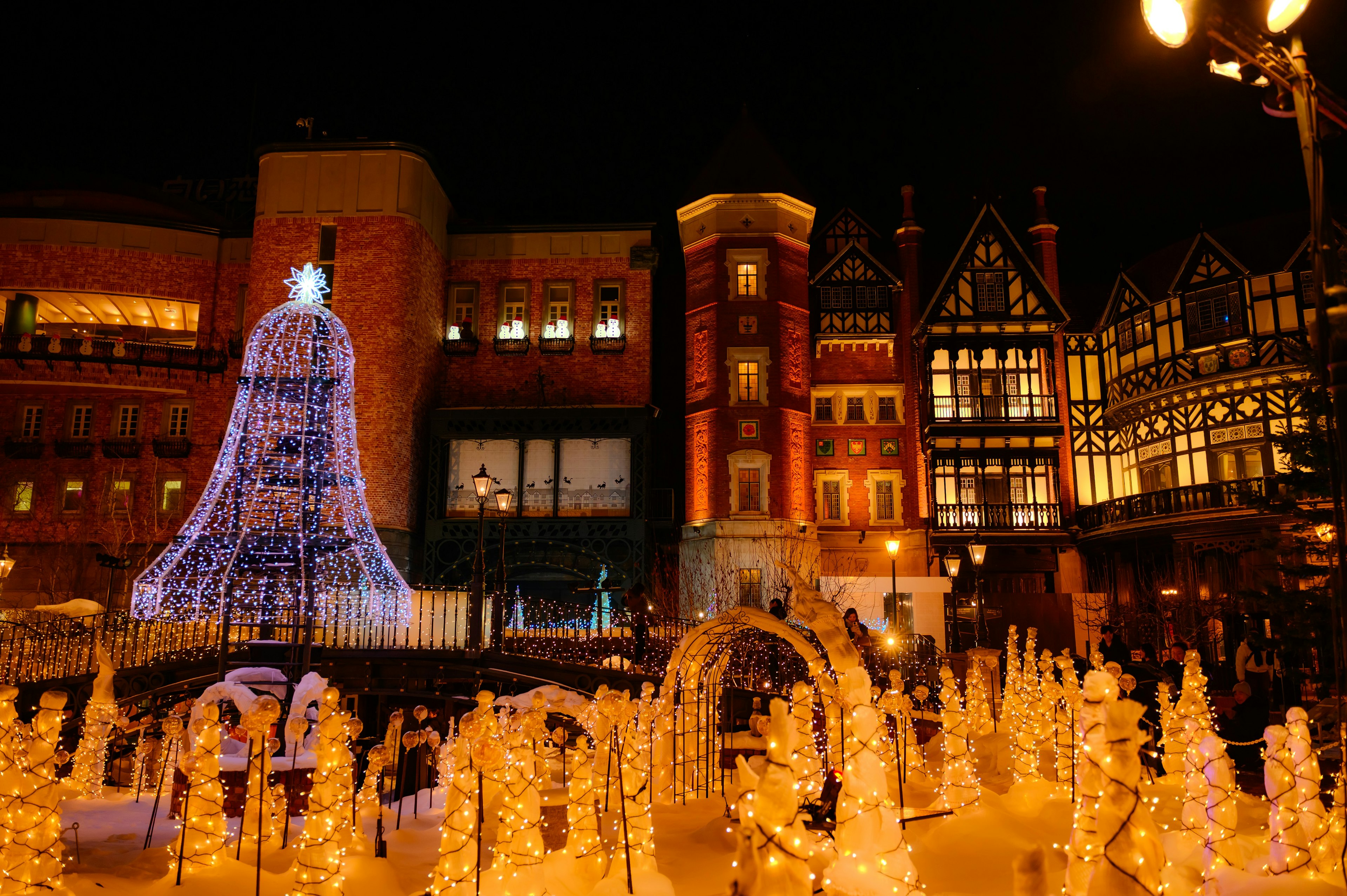 Christmas bell illuminated at night surrounded by festive decorations and buildings