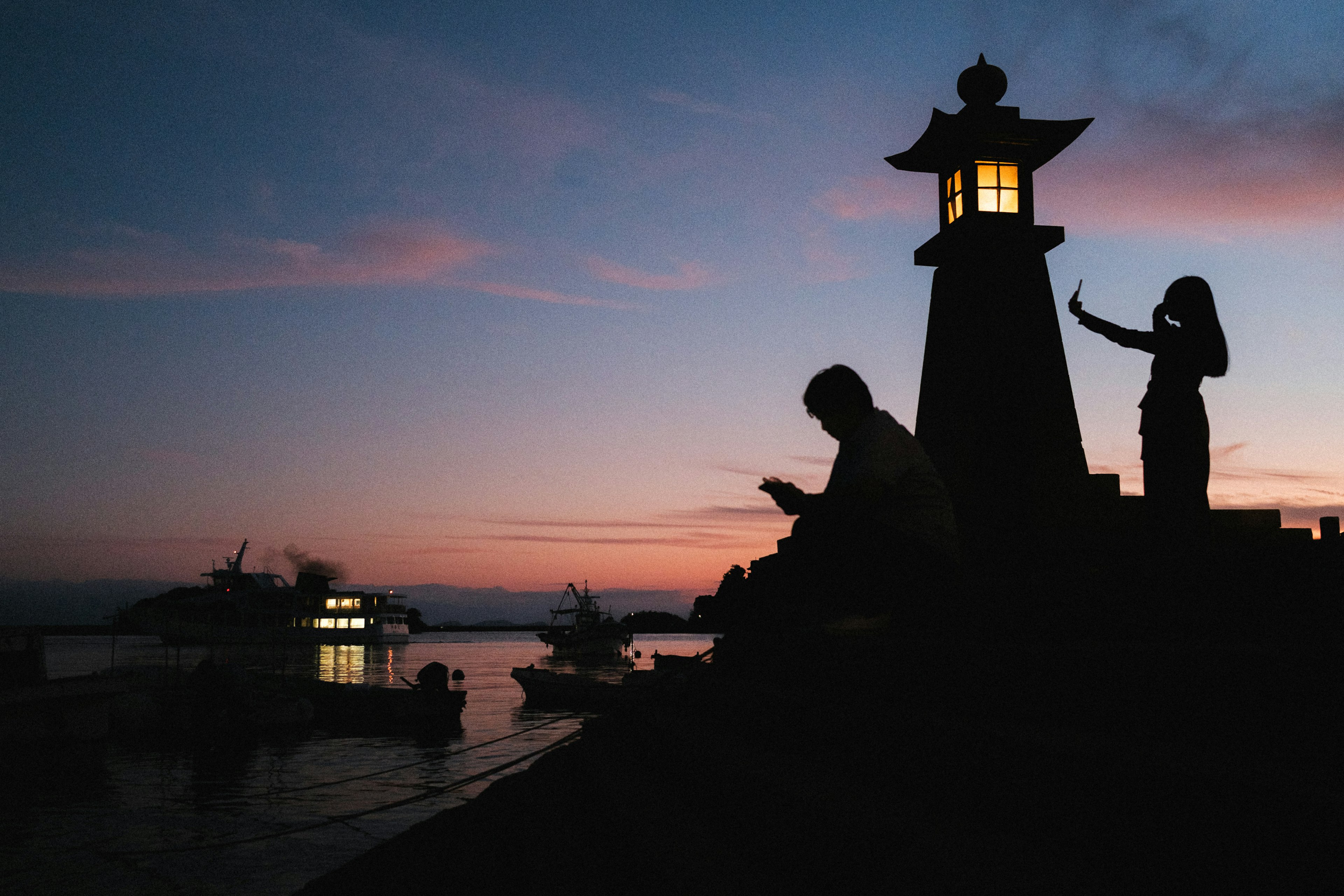 Silhouette of people enjoying at a lighthouse during sunset