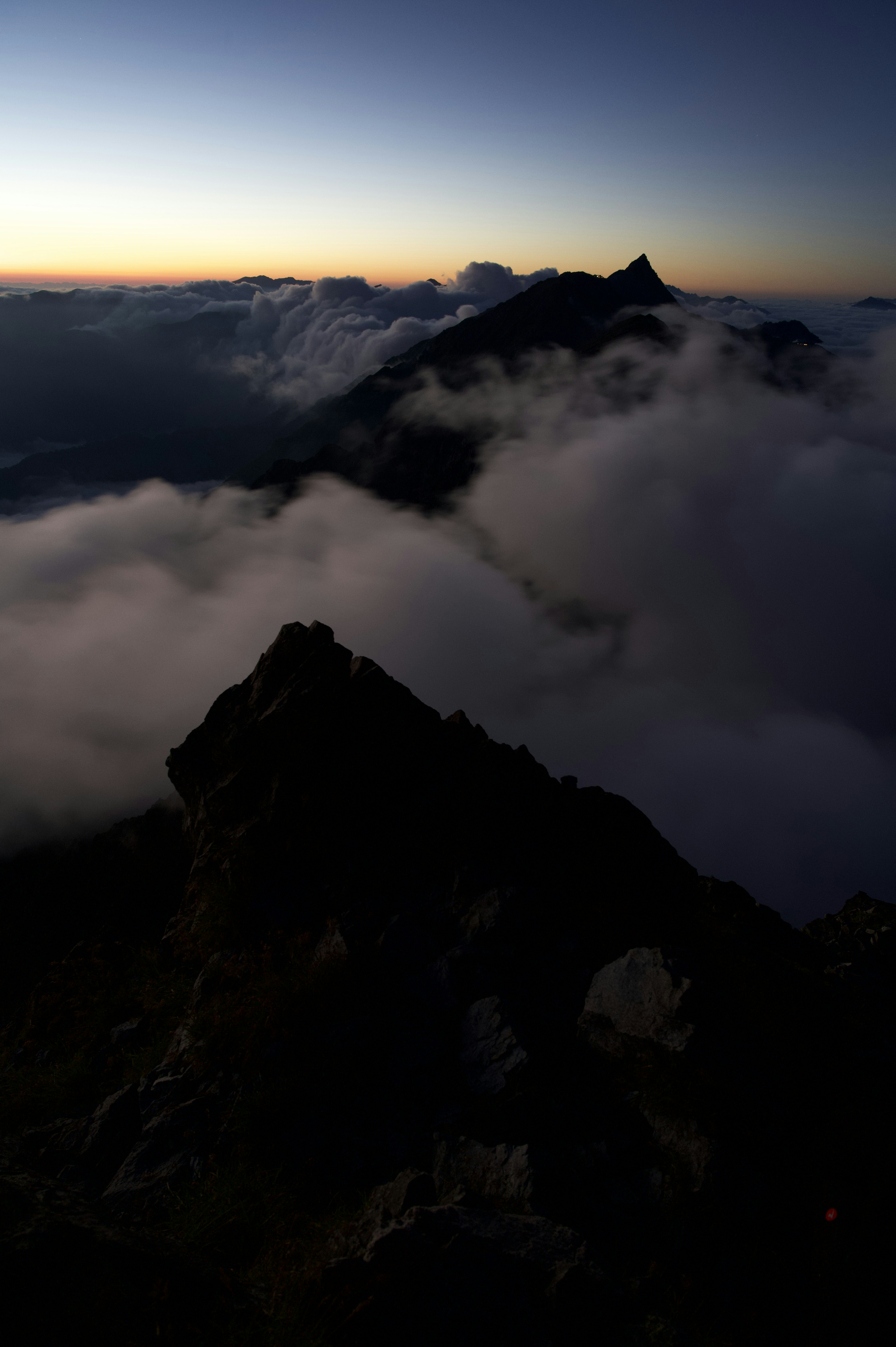 Vista da una cima montuosa con nuvole e tramonto