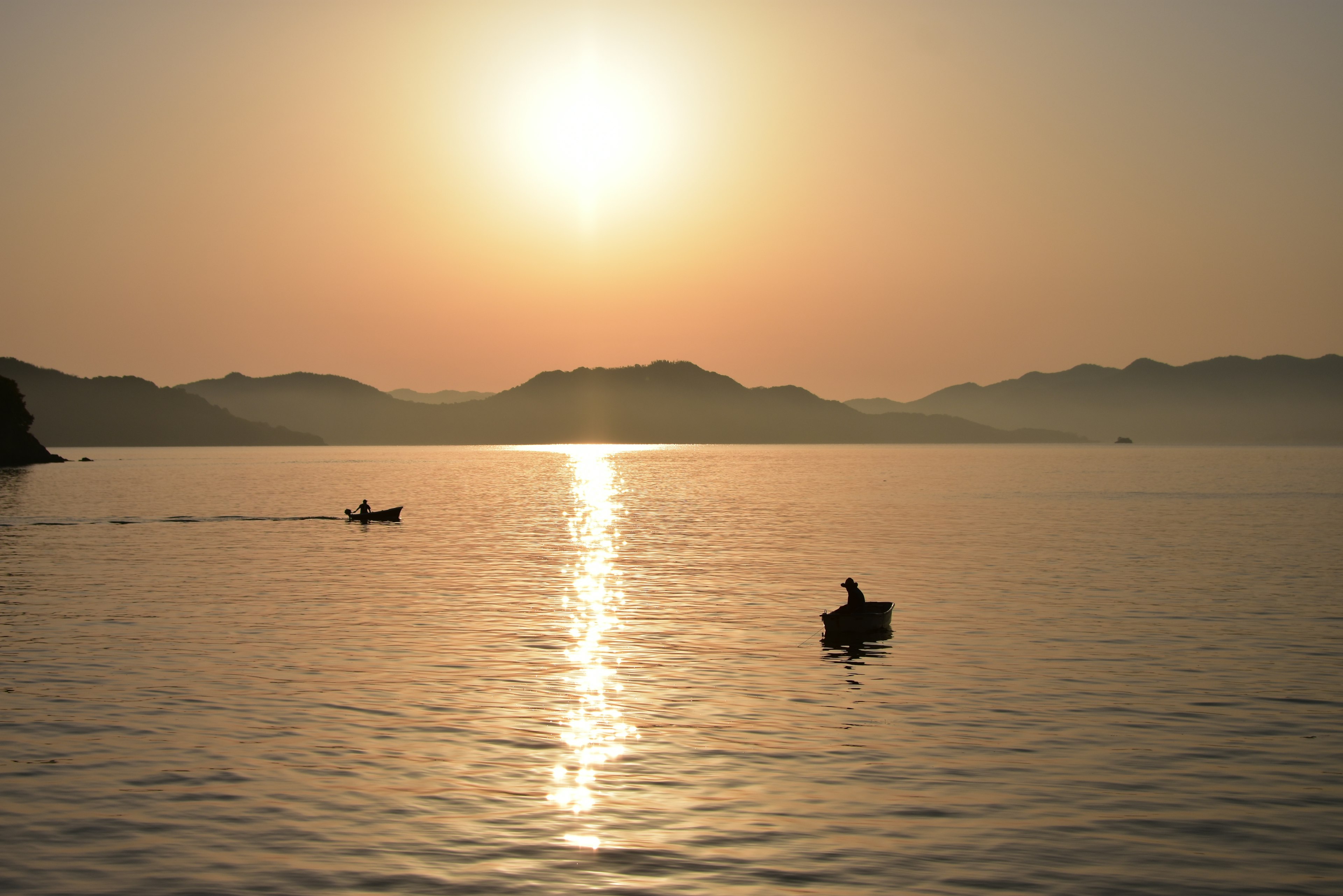 Zwei Boote paddeln auf einem ruhigen See bei Sonnenuntergang