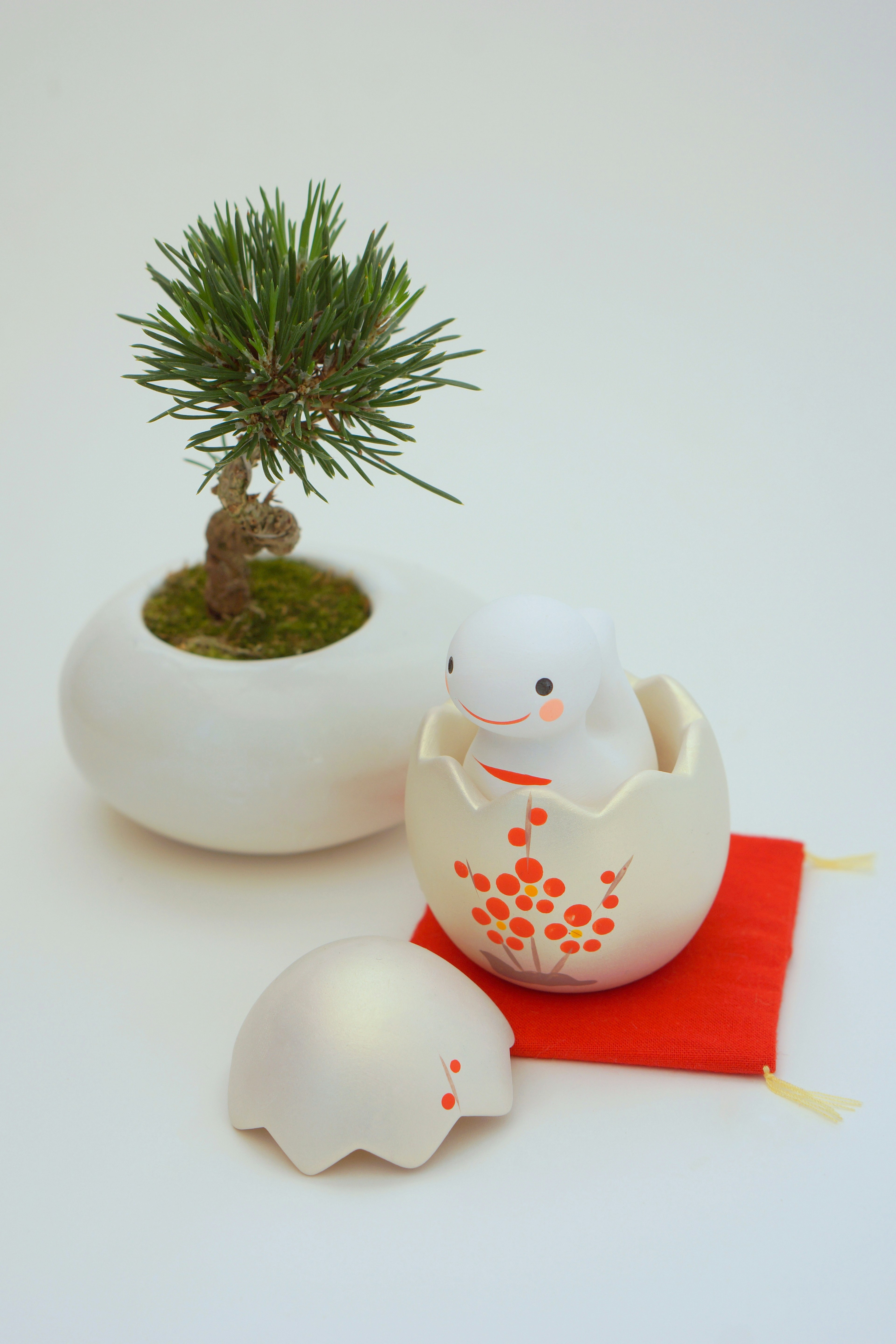 White ceramic egg-shaped ornament with a small bonsai tree