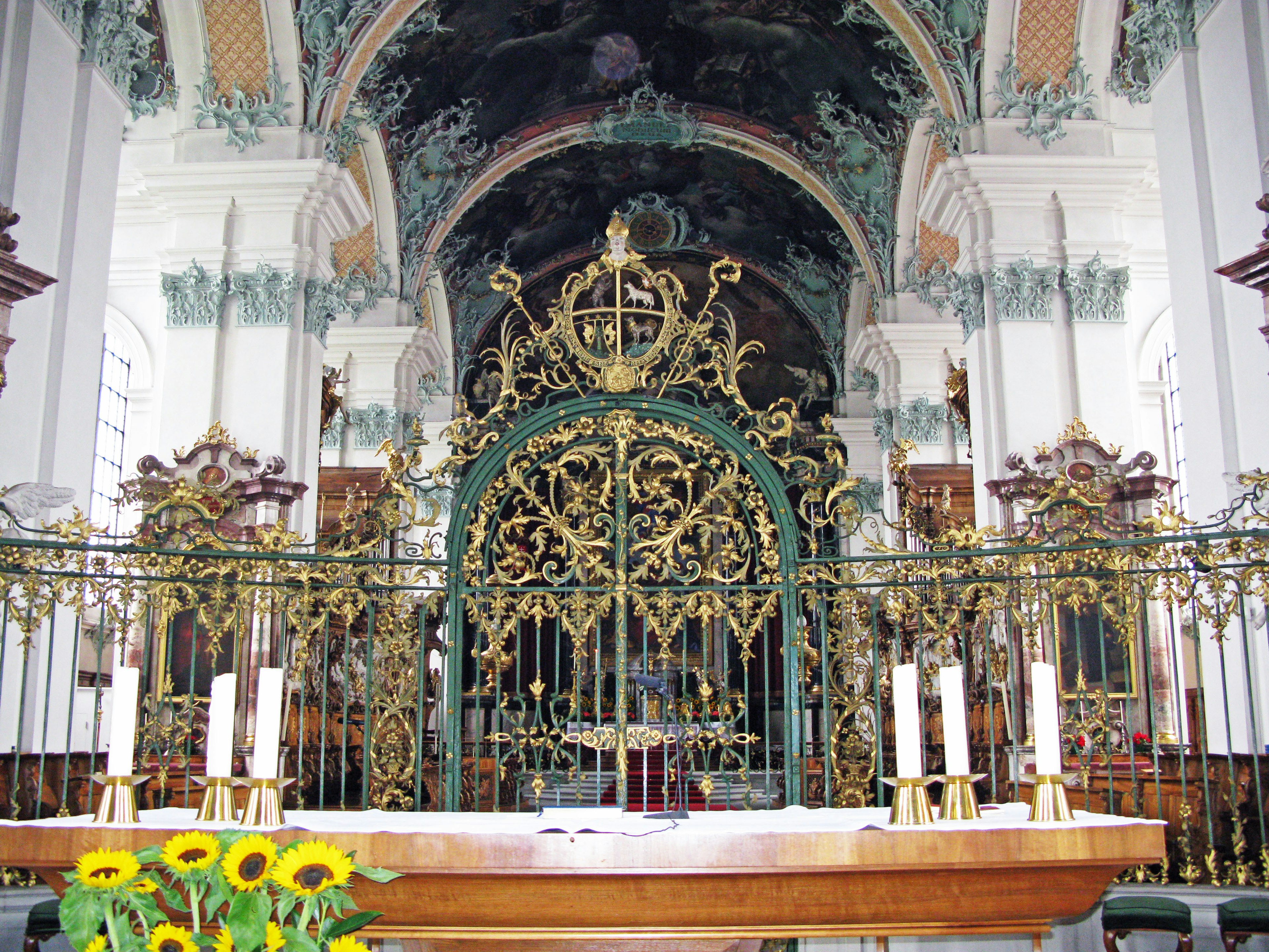 Altar de iglesia bellamente decorado con reja dorada ornamentada