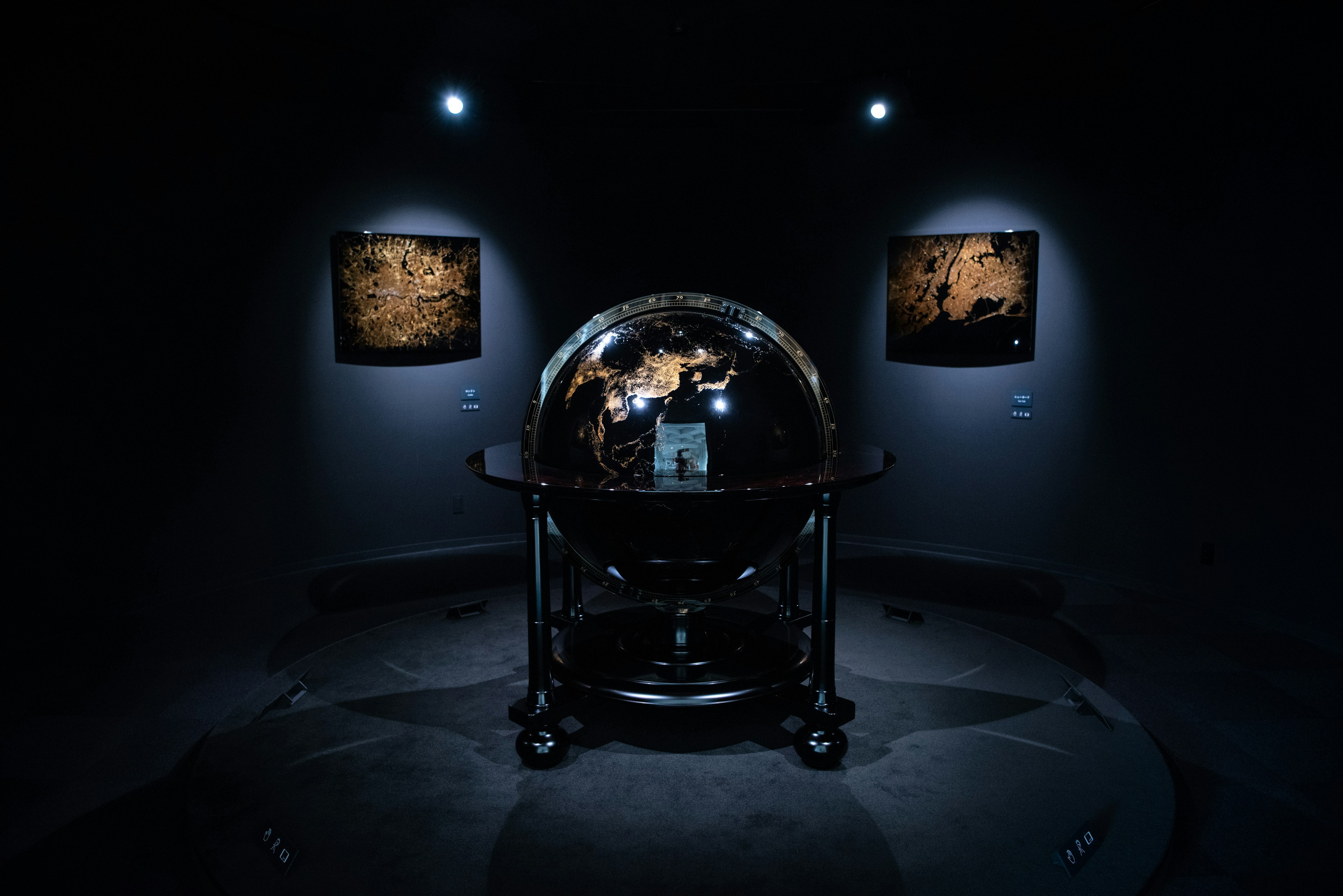 A globe displayed in a dark room with surrounding artwork