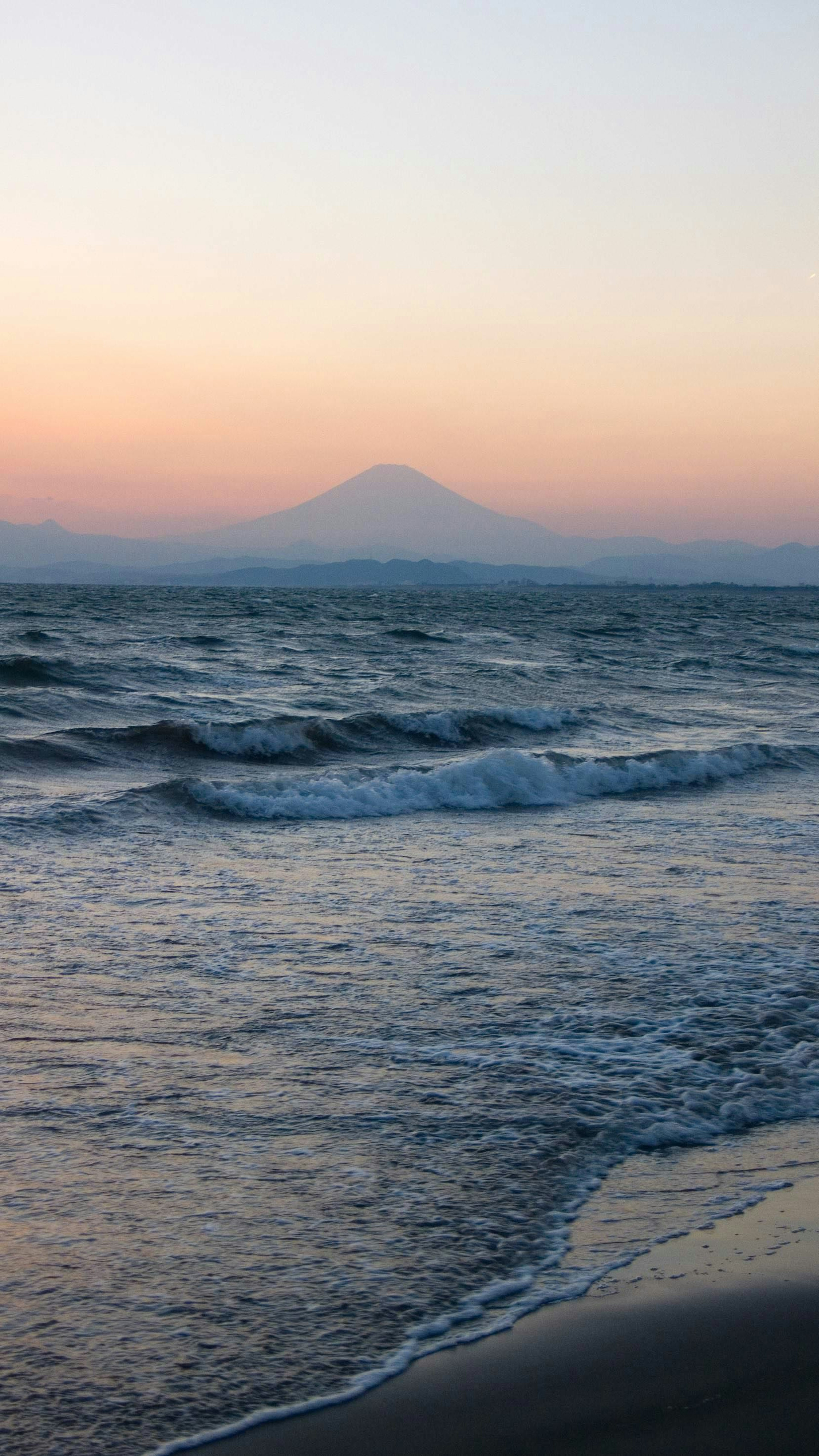 Mar tranquilo con fondo montañoso al atardecer