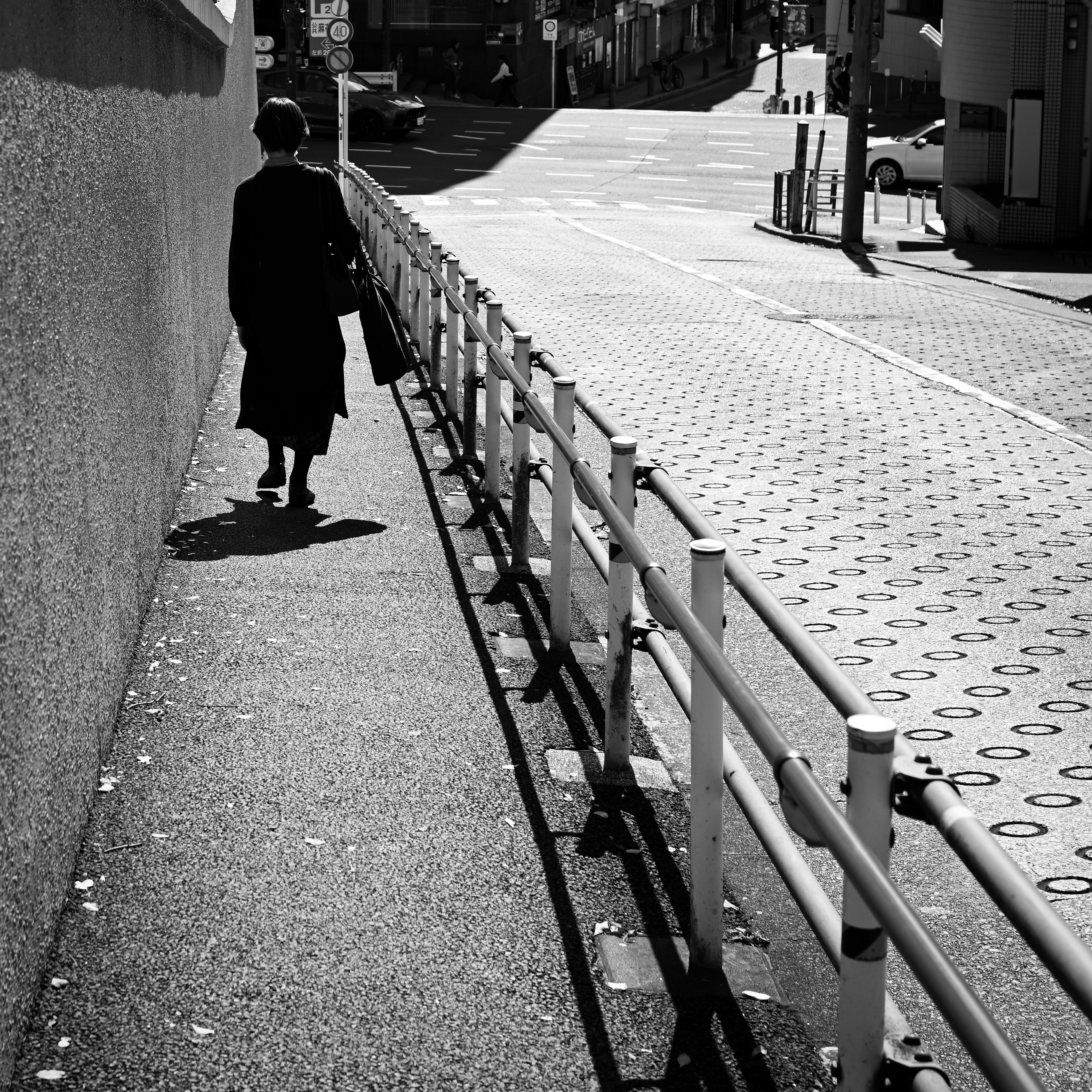 Personne marchant sur un trottoir noir et blanc avec des ombres