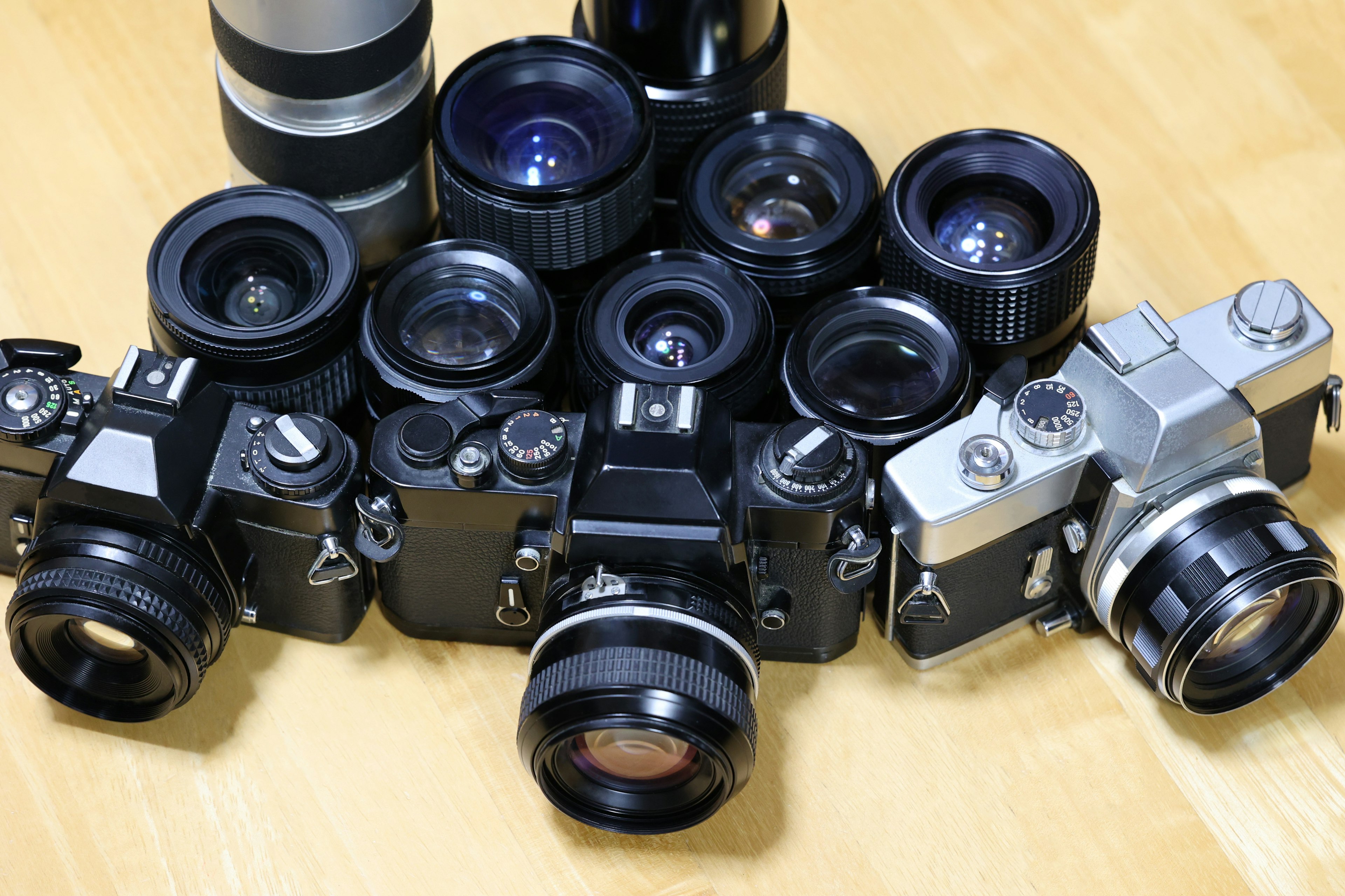 A collection of vintage cameras and lenses arranged on a wooden surface