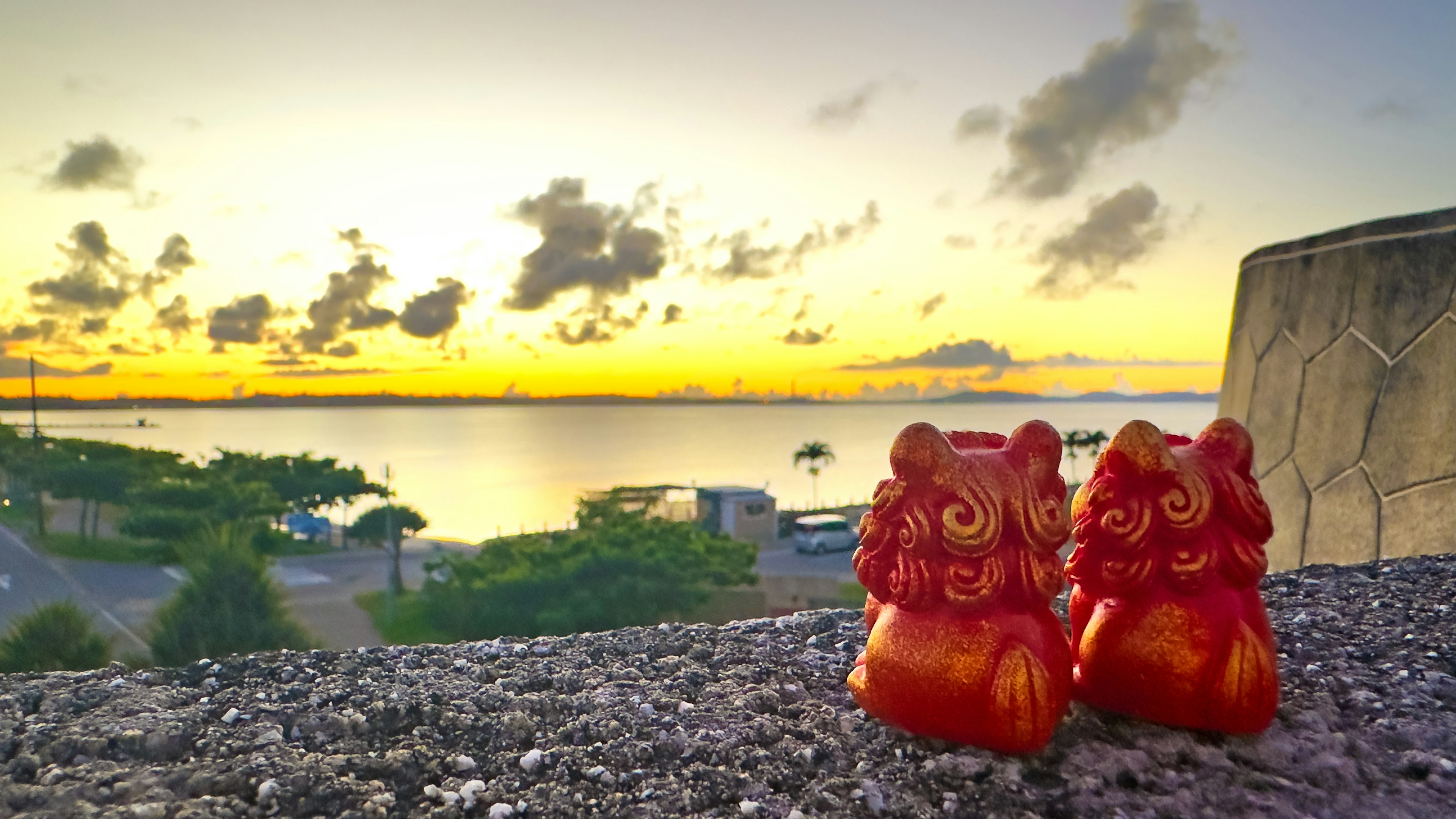 夕日を背景にした赤い獅子の像が並んでいる