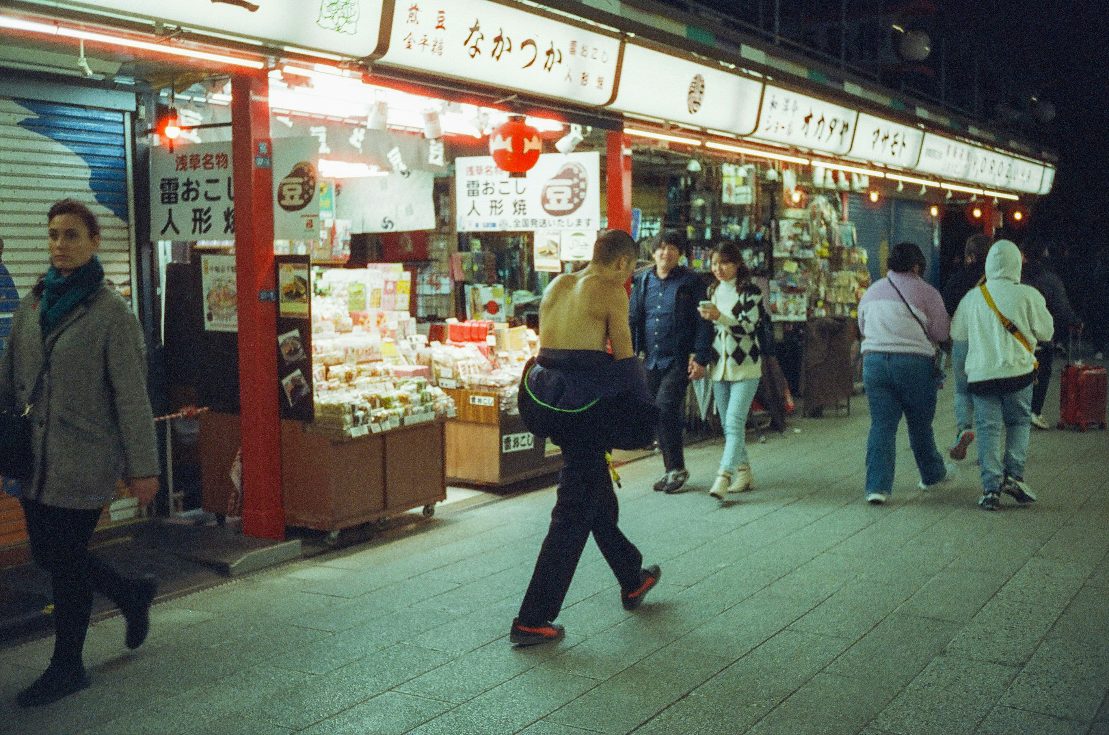 夜の商店街を歩く人々と明るい看板