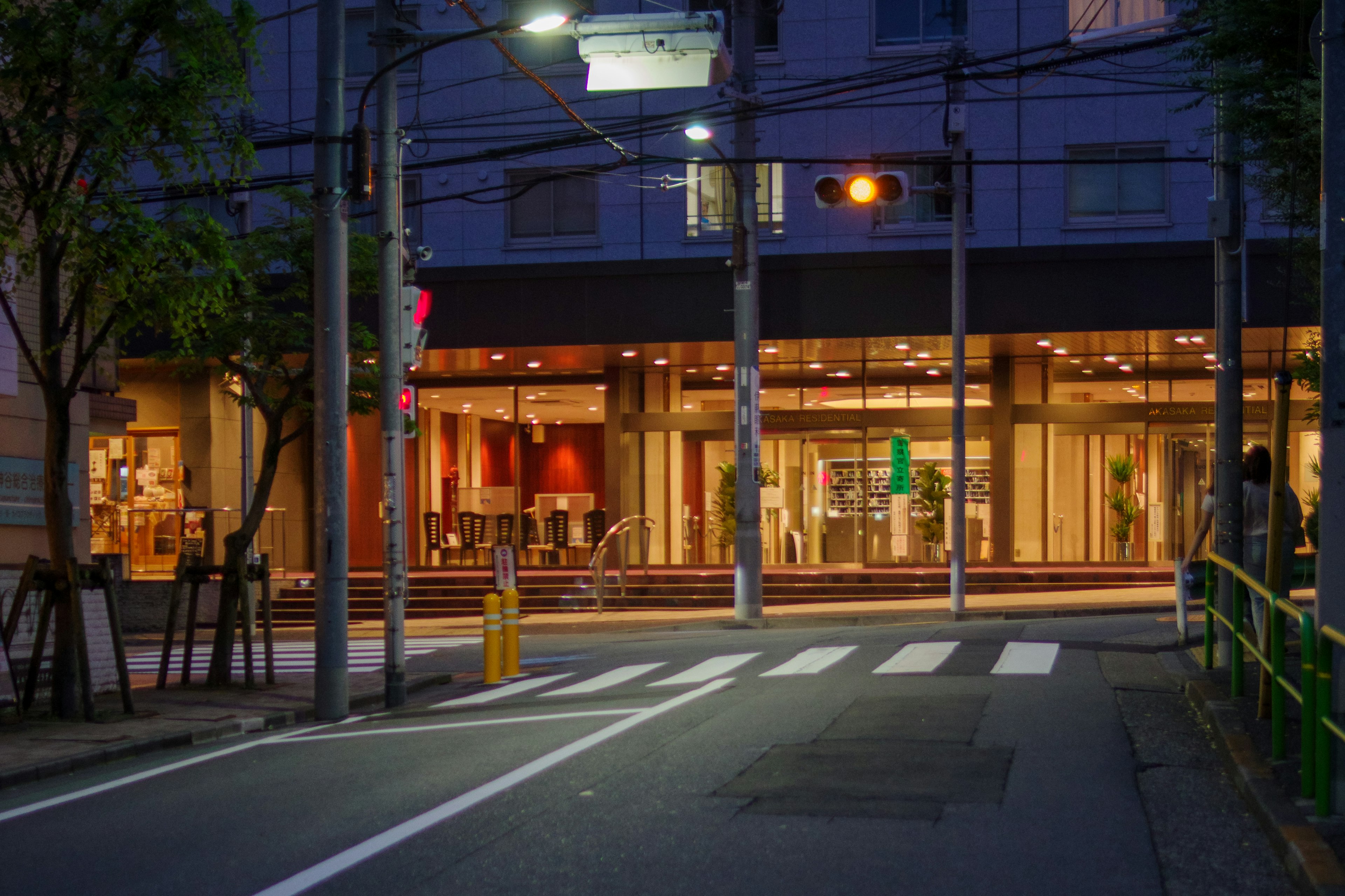 夜の街角にある明るいホテルの外観と横断歩道