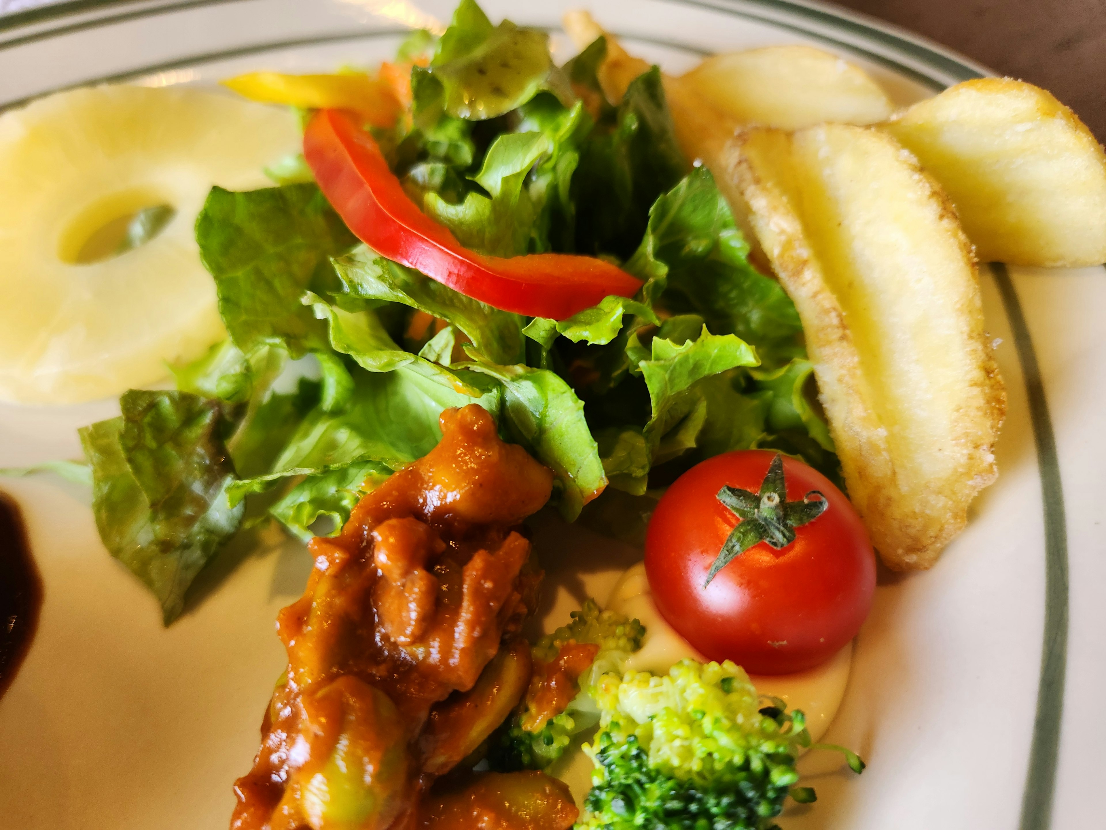 A plate featuring colorful salad, fried potatoes, and grilled chicken with vegetables