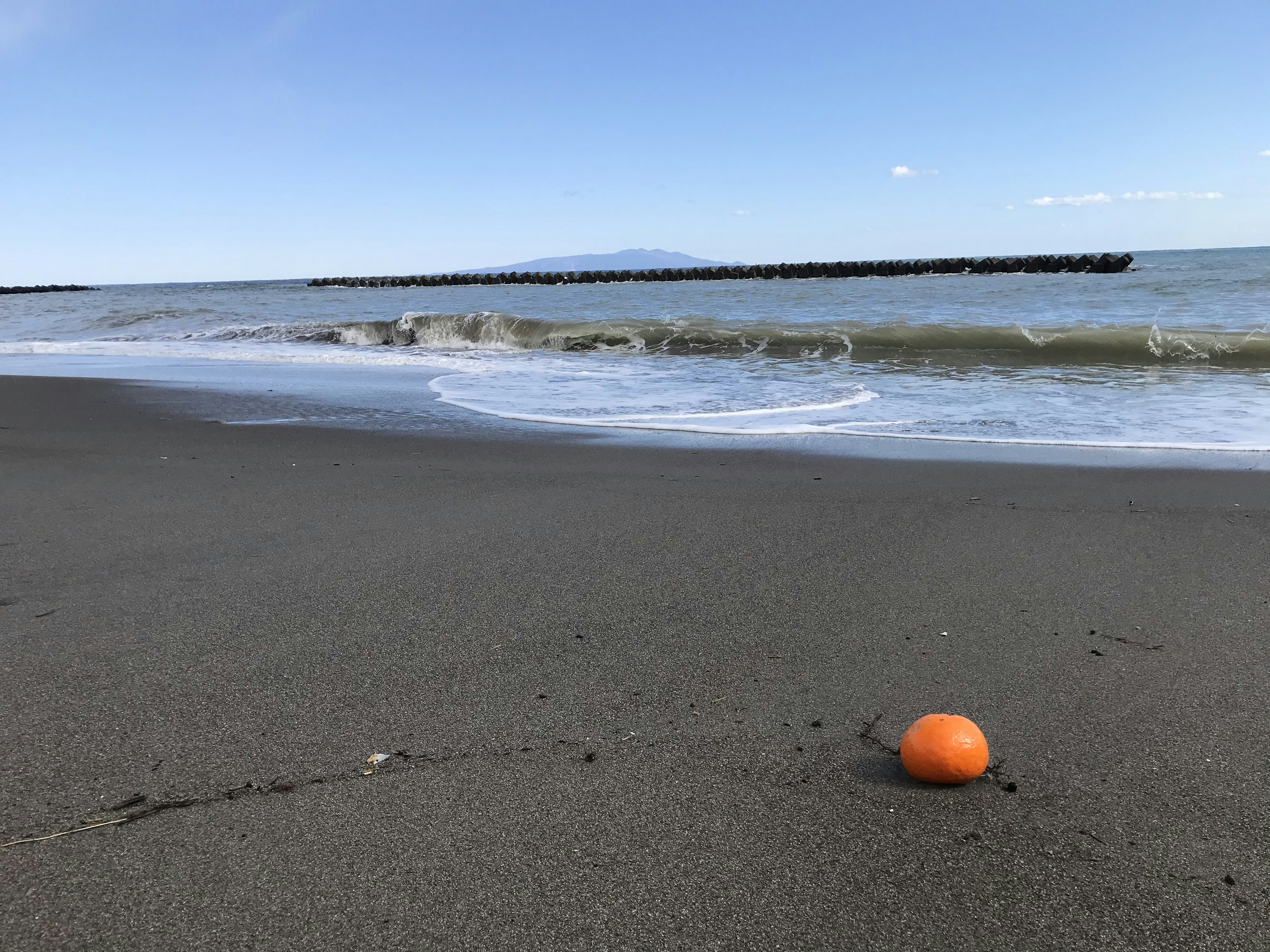 Ein orangefarbener Ball an einem Sandstrand mit sanften Wellen