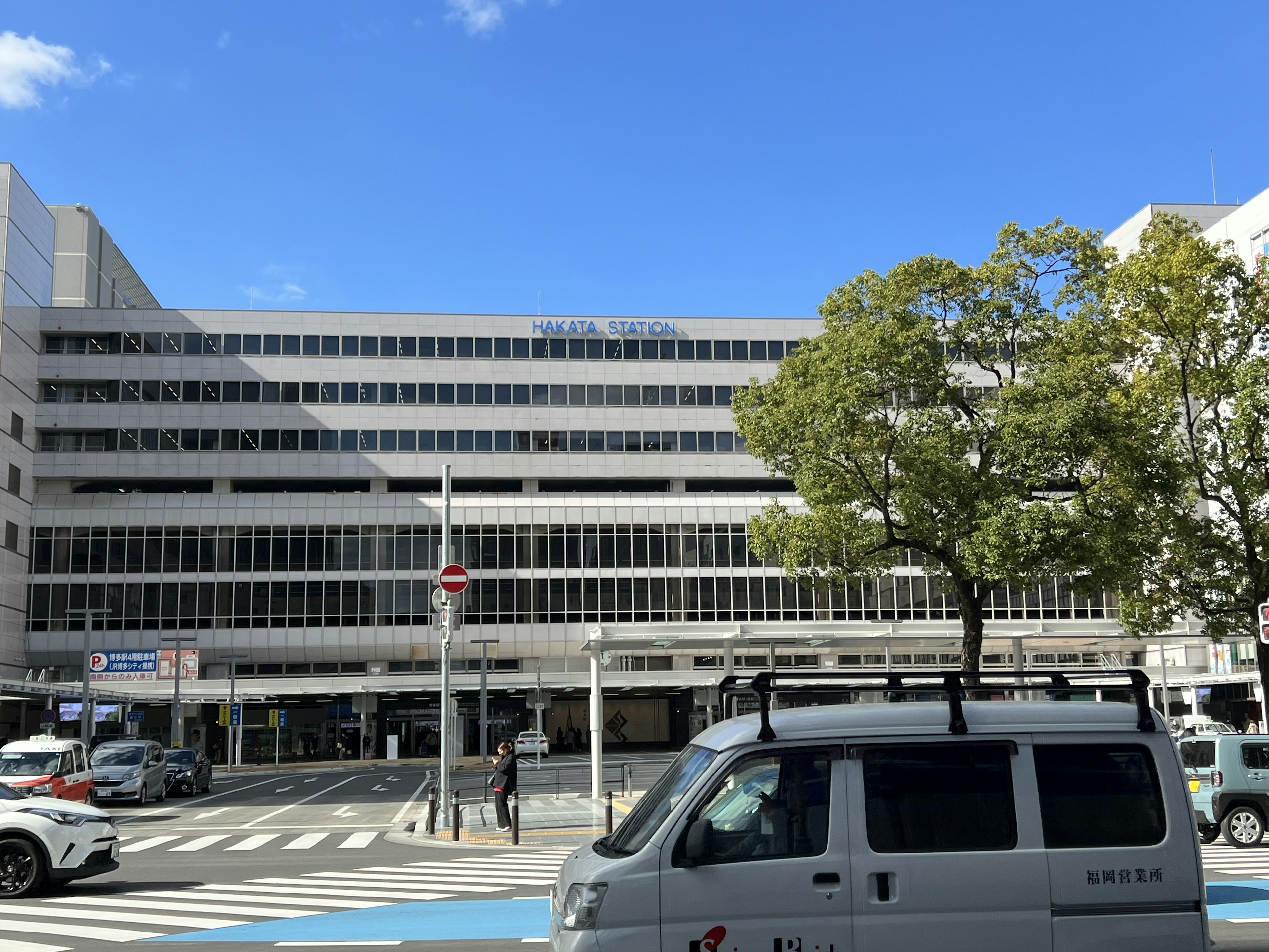 Bâtiment moderne faisant face à une rue urbaine avec ciel bleu