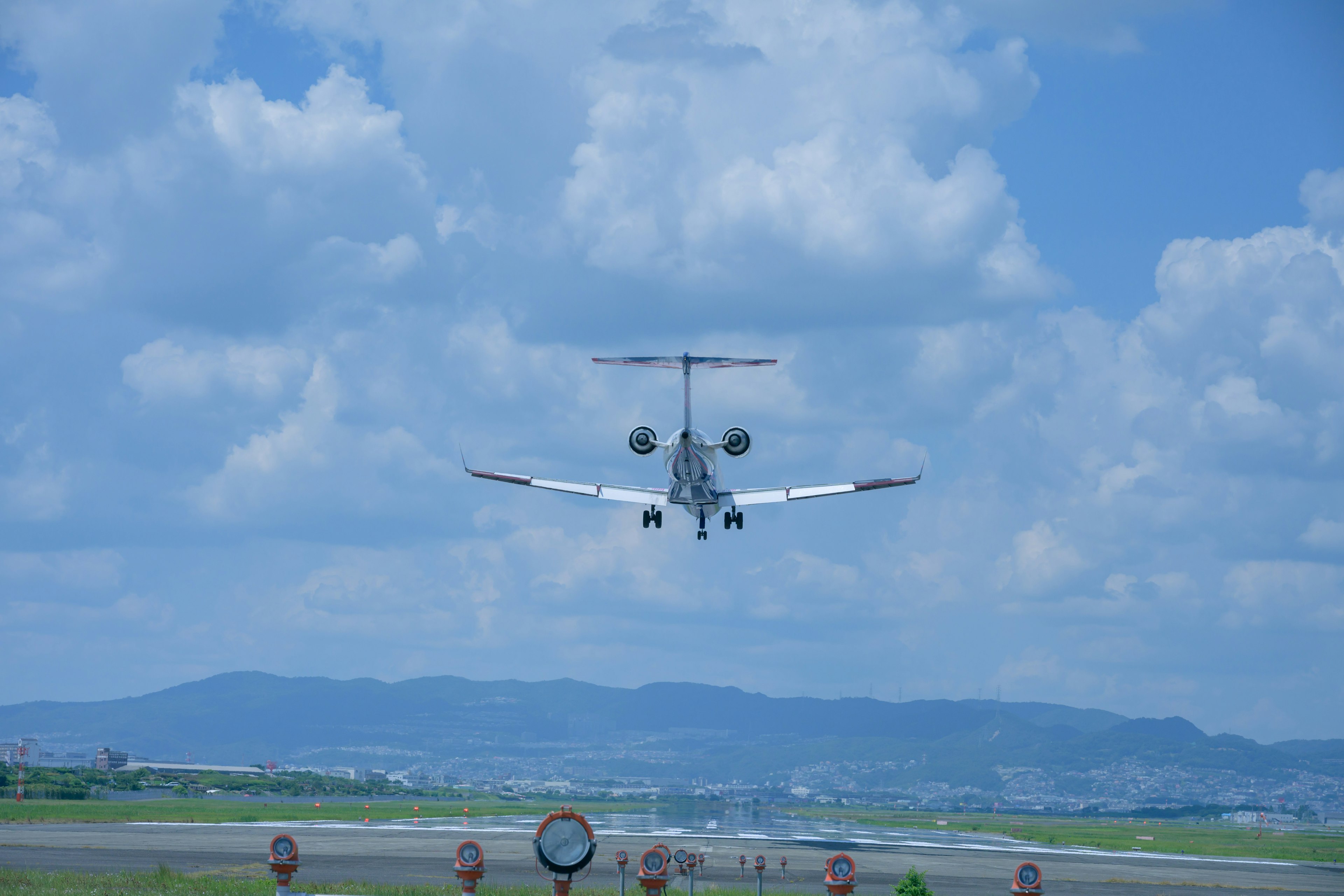 Aereo in fase di atterraggio su una pista con cielo blu e nuvole bianche sullo sfondo