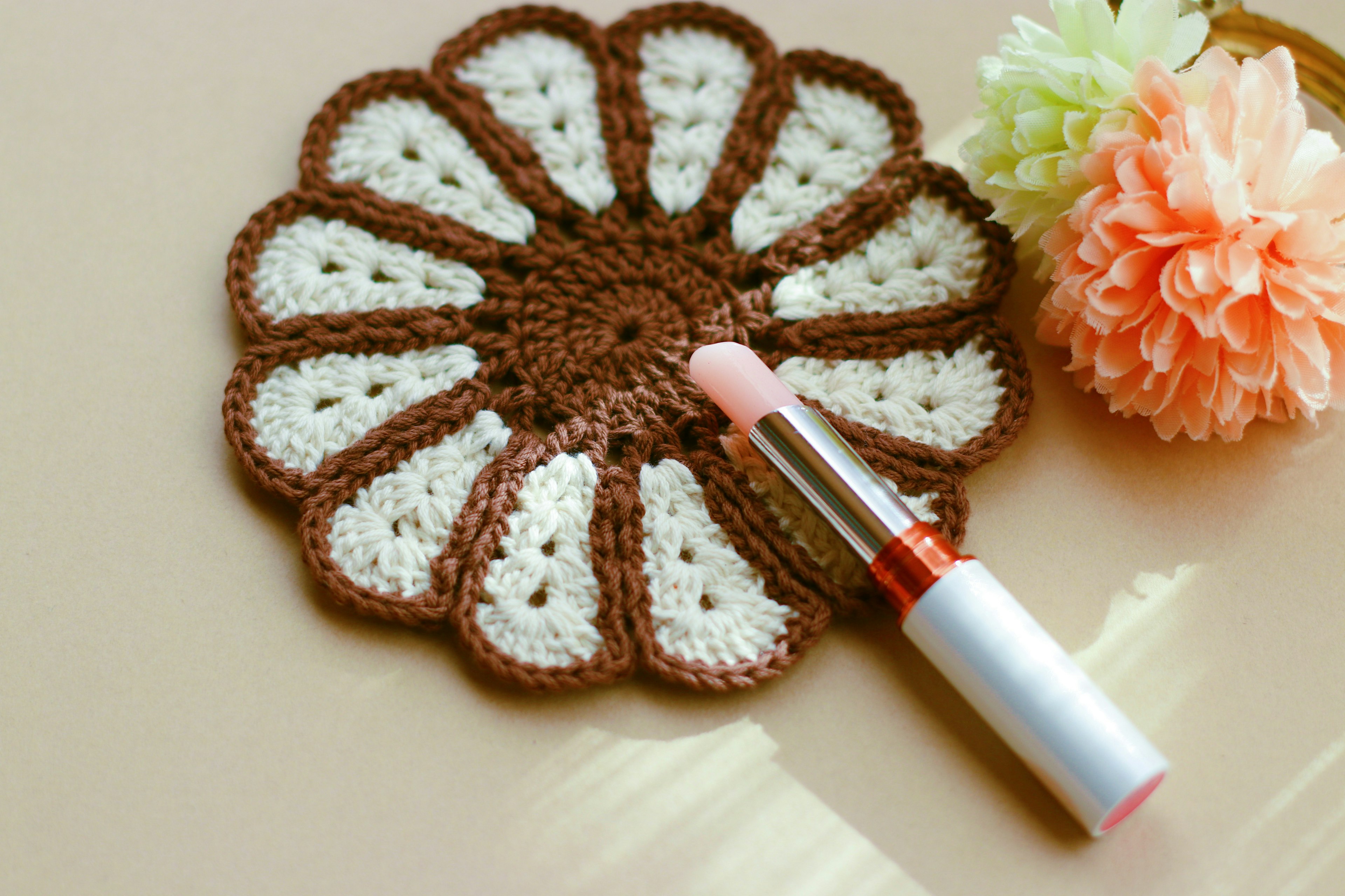 Flower-shaped crochet coaster with pink lipstick