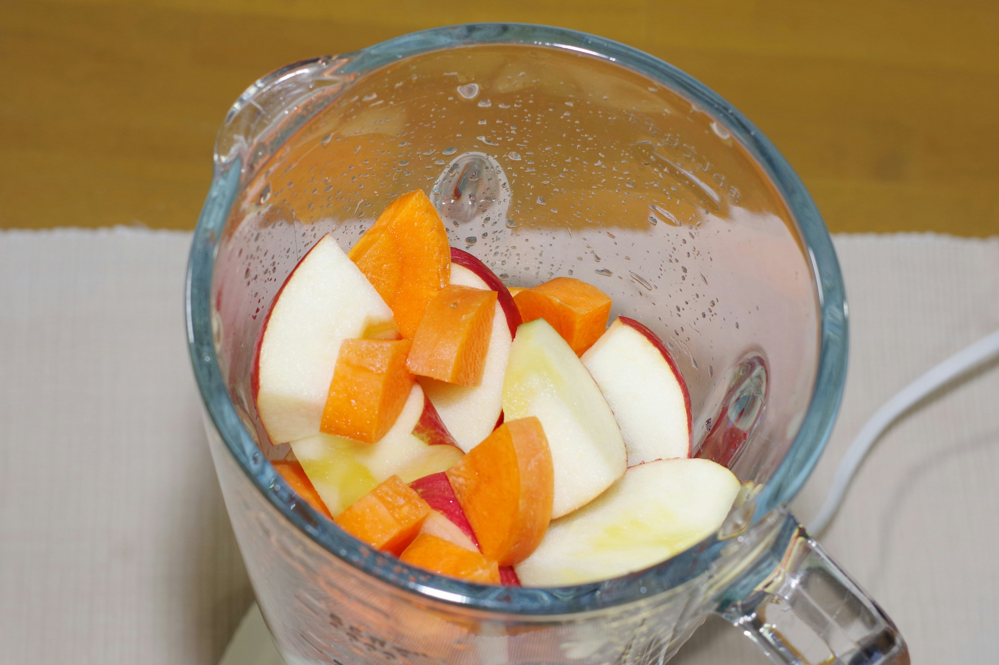 Manzanas rojas y zanahorias naranjas cortadas en una licuadora