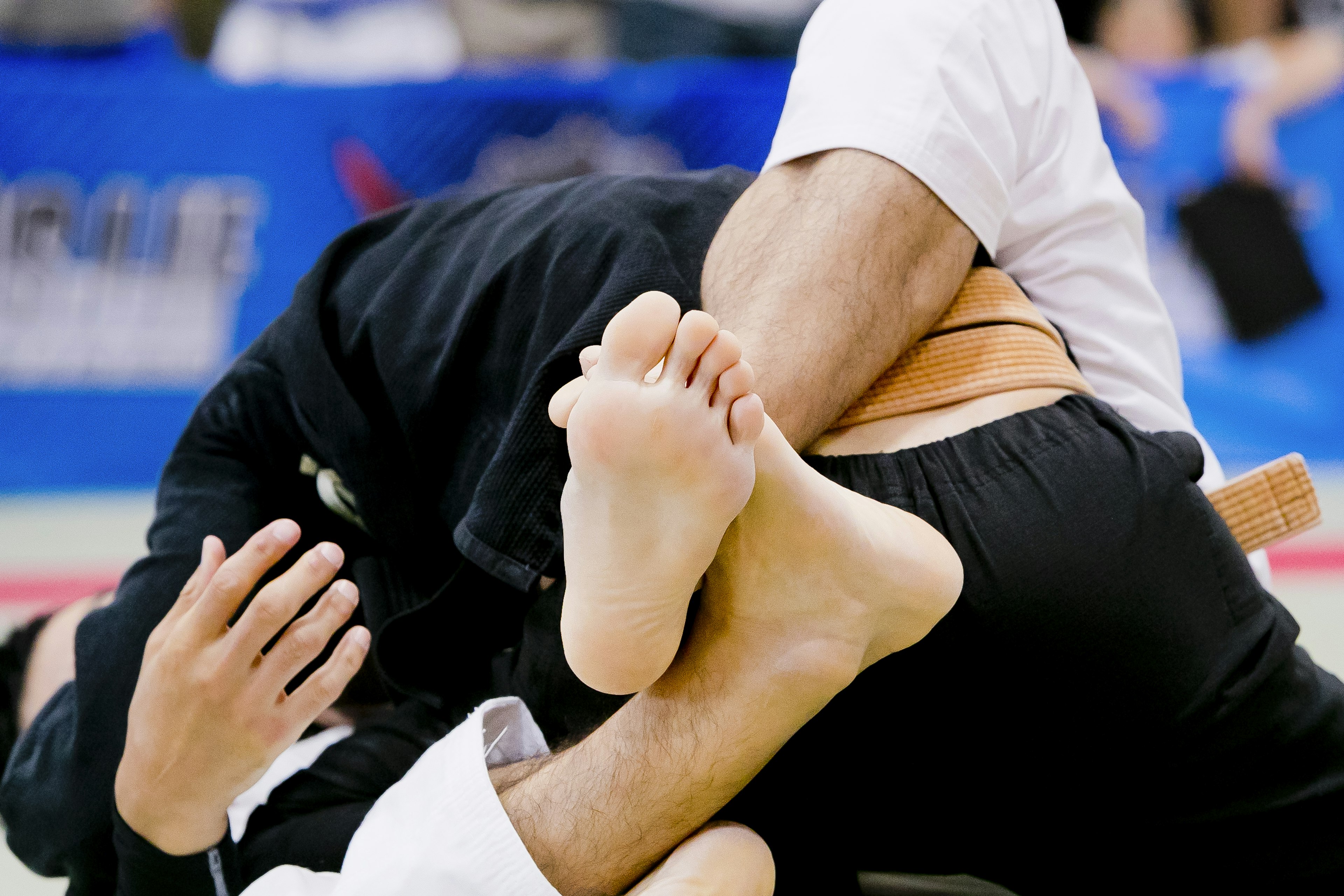 Dos luchadores de judo entrelazados en una posición de grappling con los pies entrelazados