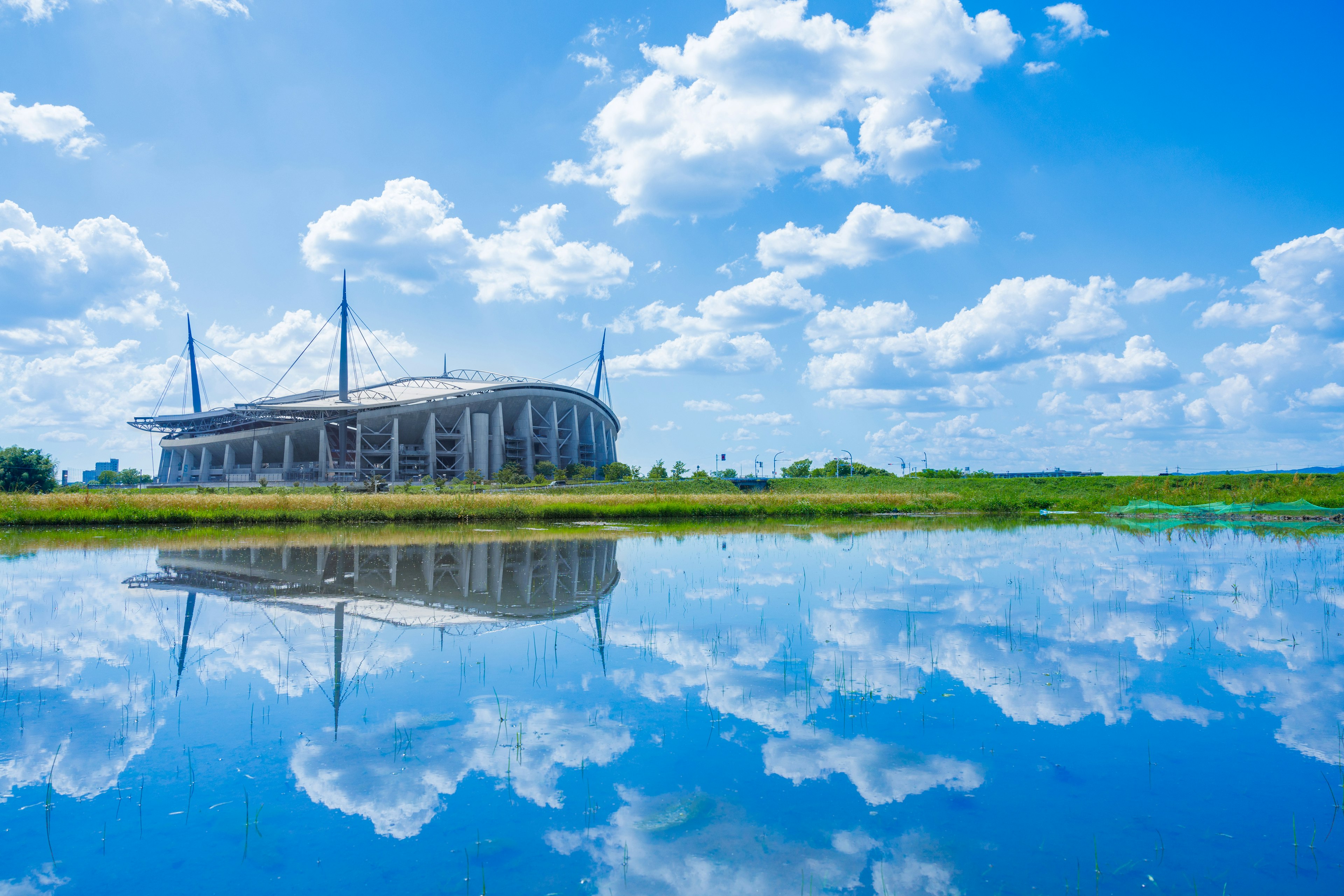 Stadio riflesso nell'acqua sotto un cielo blu con nuvole