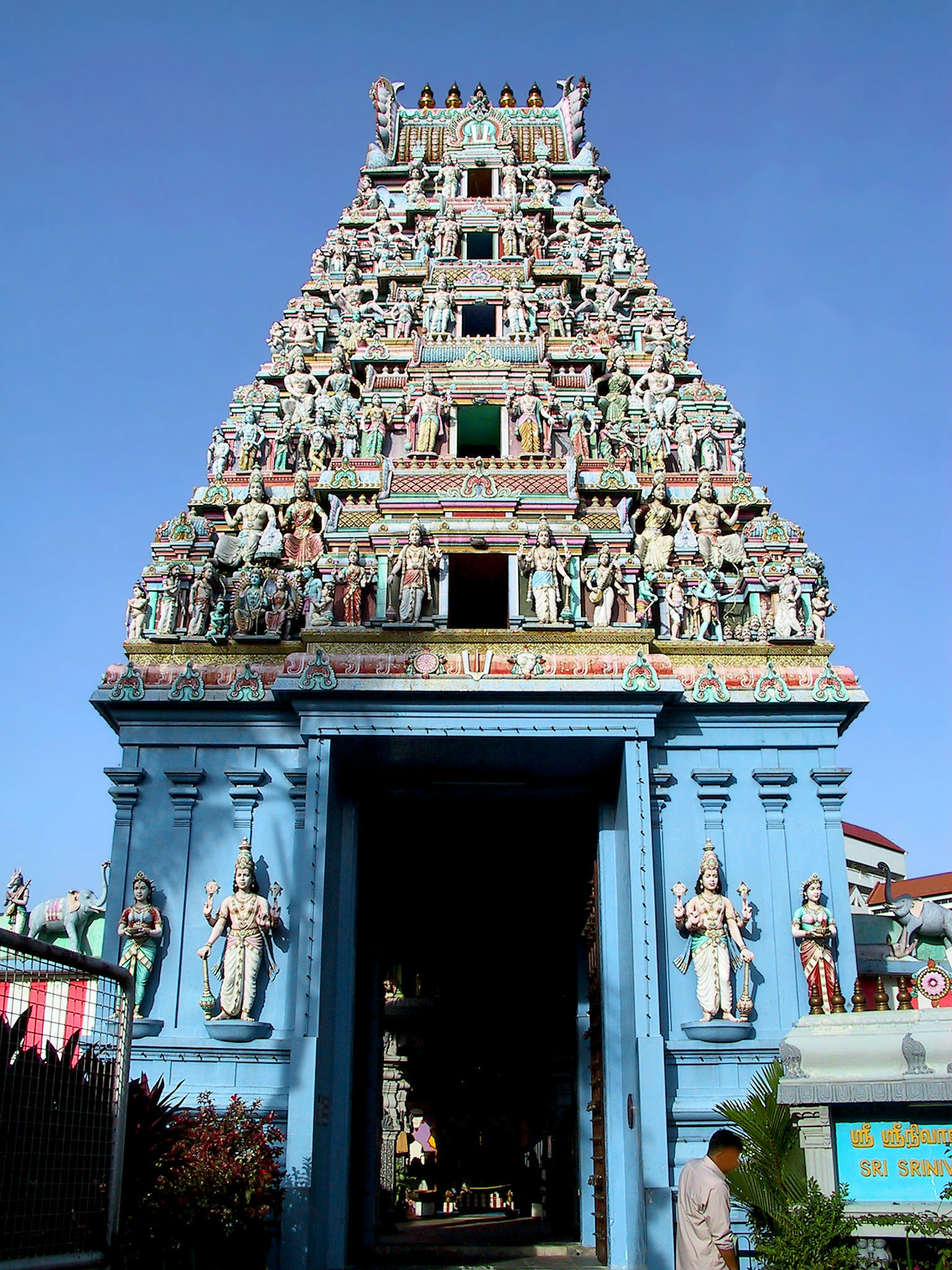 Front entrance of a blue temple adorned with colorful sculptures